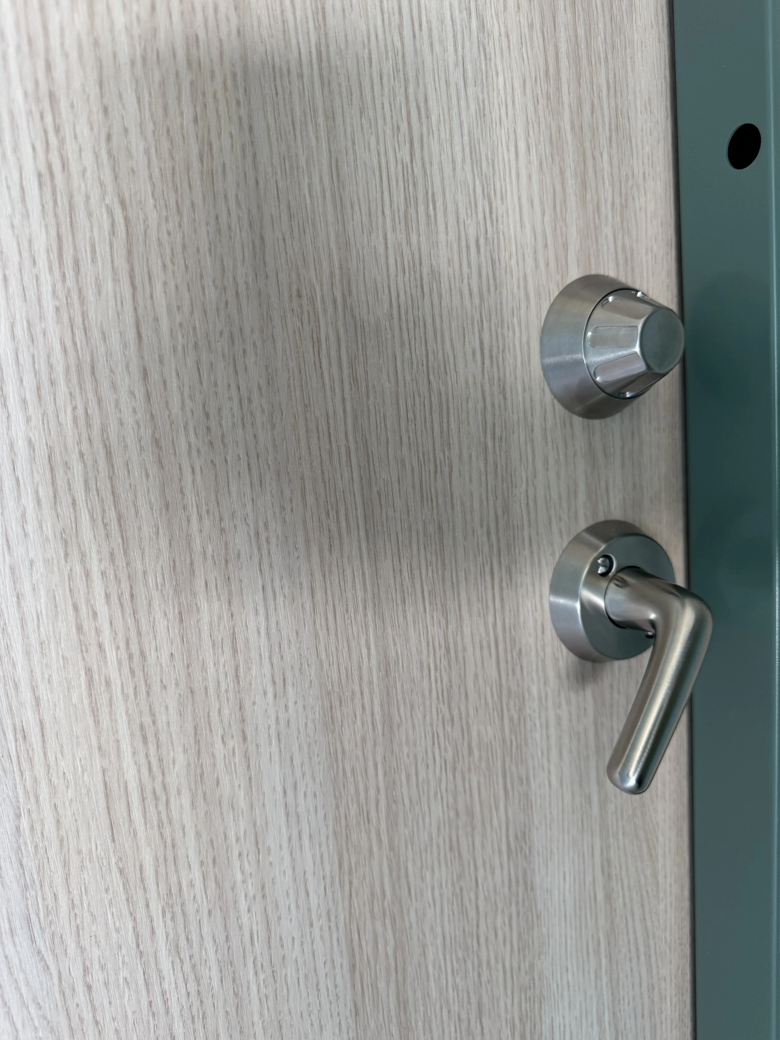 Nærbilde av en lys treferdør med metallhåndtak og lås. 
