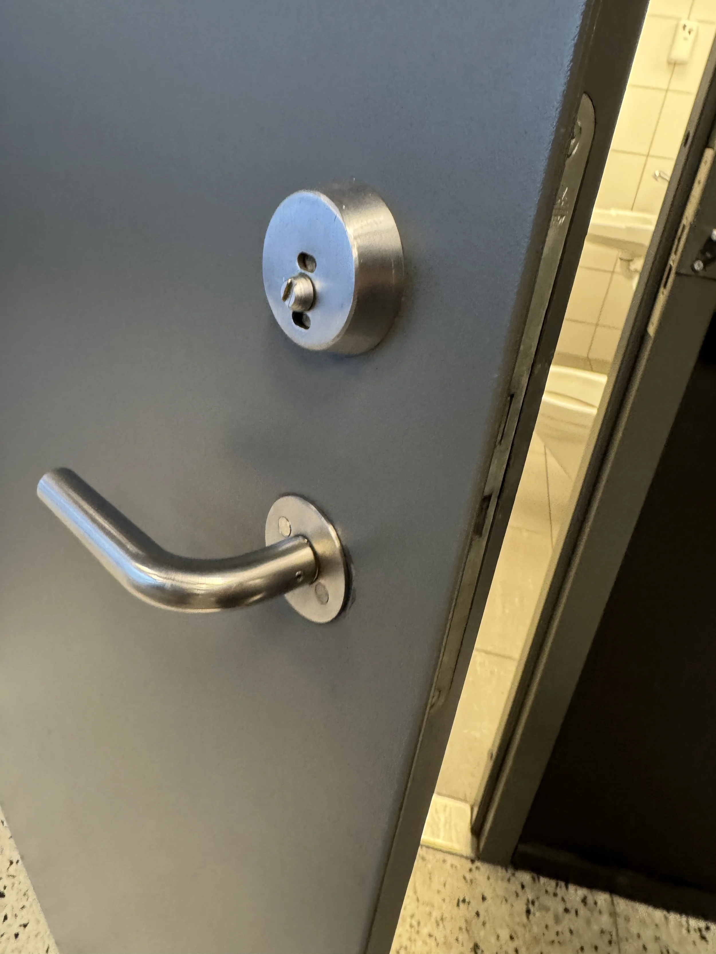Nærbilde av en dusj- eller bade dør med låse- og håndtak.