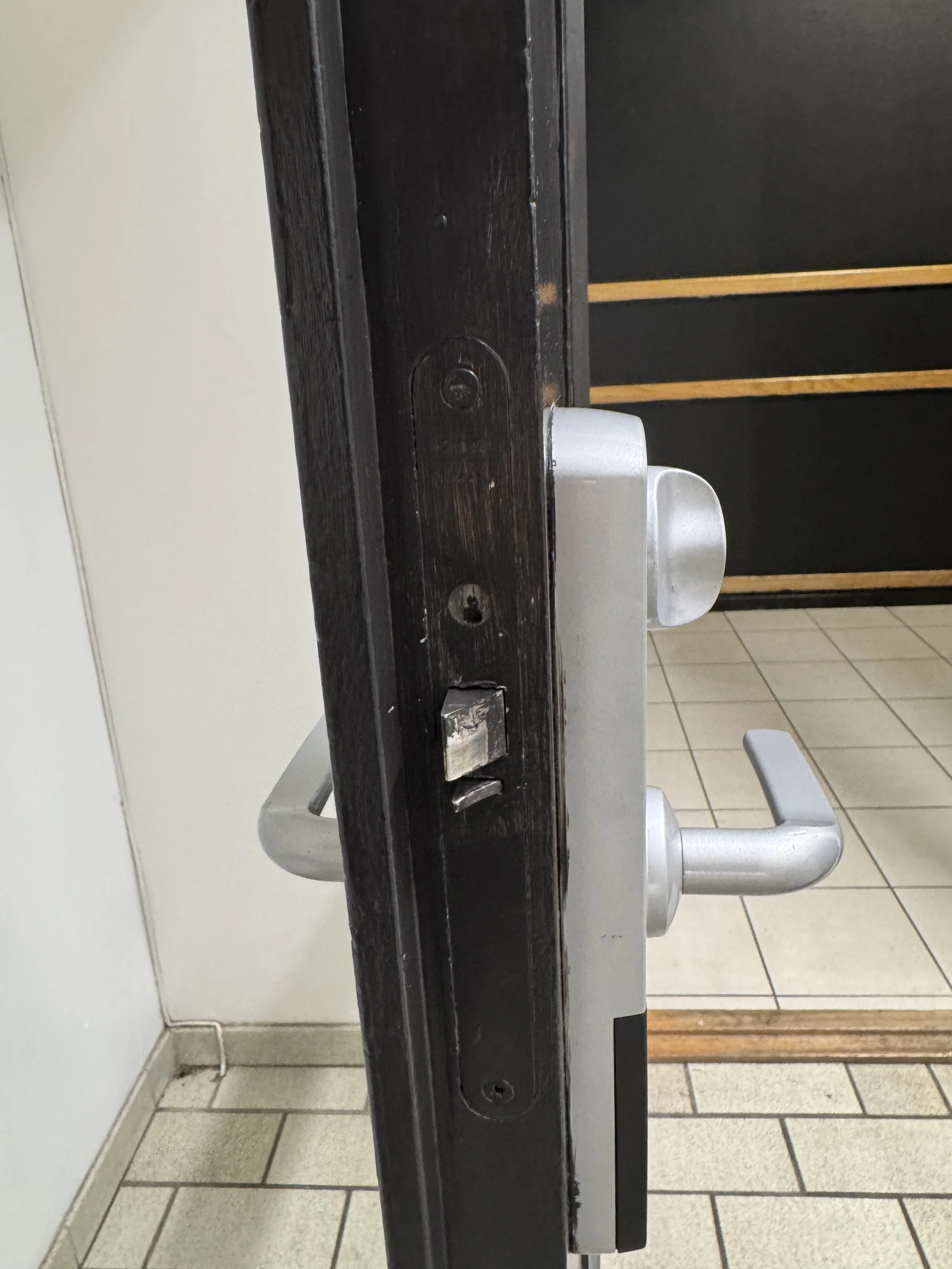 Døren er delvis åpen, med et metallvrikilås og et håndtak.