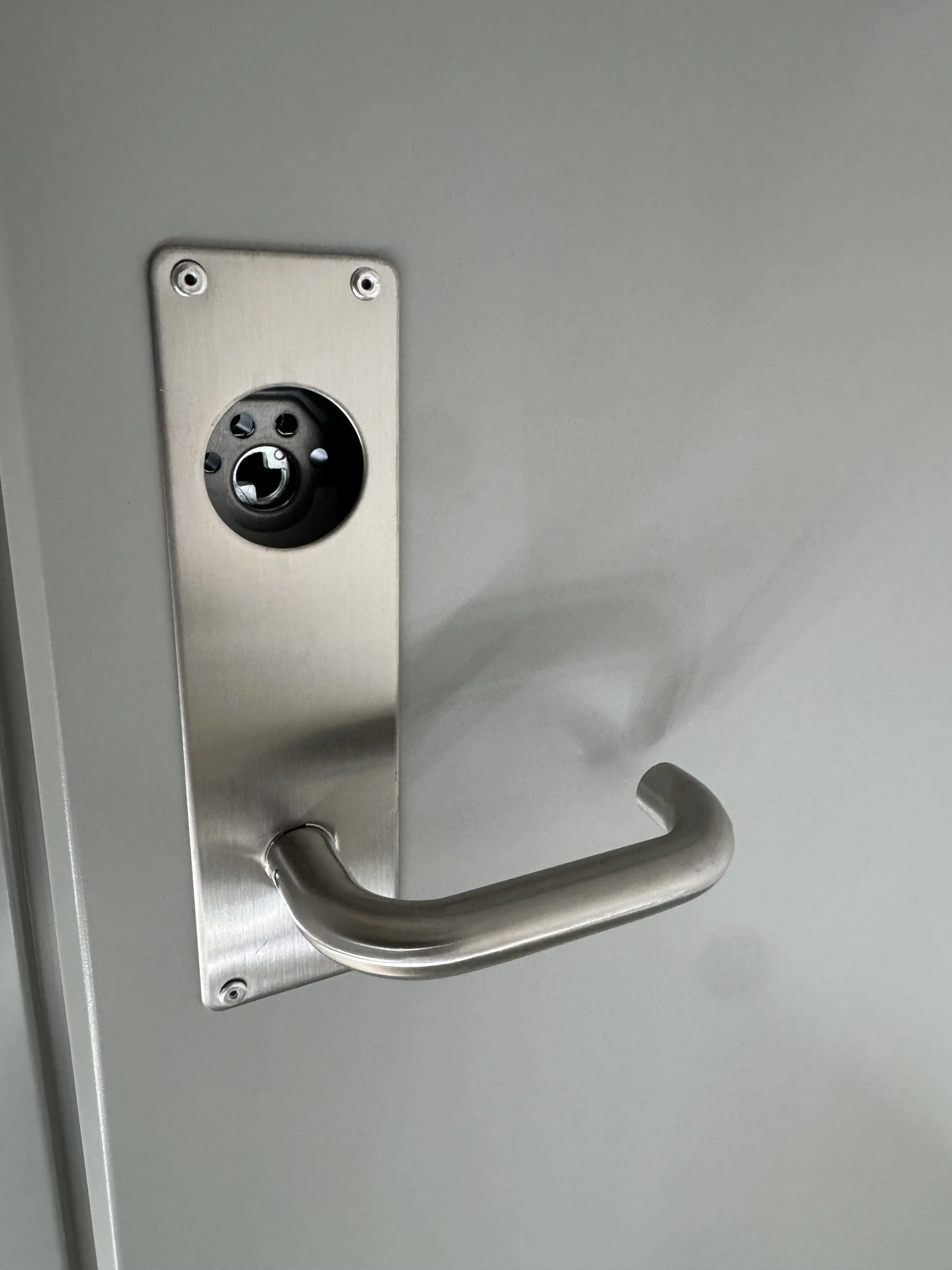 En dør med en metallhåndtak og en elektrisk låseinnretning uten låsekasse, sett fra vinkel.