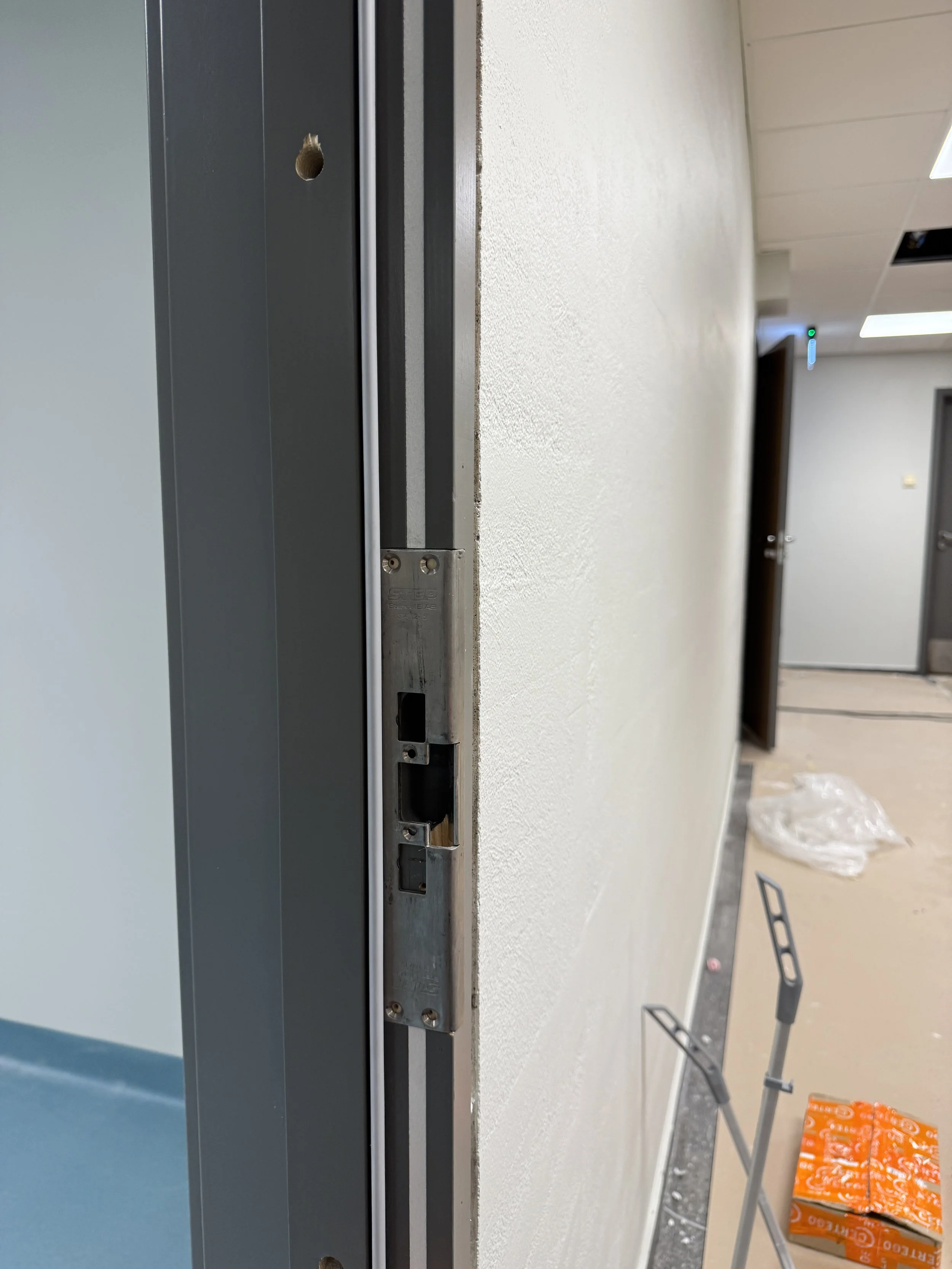 Nærbilde av en ufullstendig dørkarm i et byggegjenstand i et rom under renovering, med innlagt metallramme og noen verktøy og materialer på gulvet.