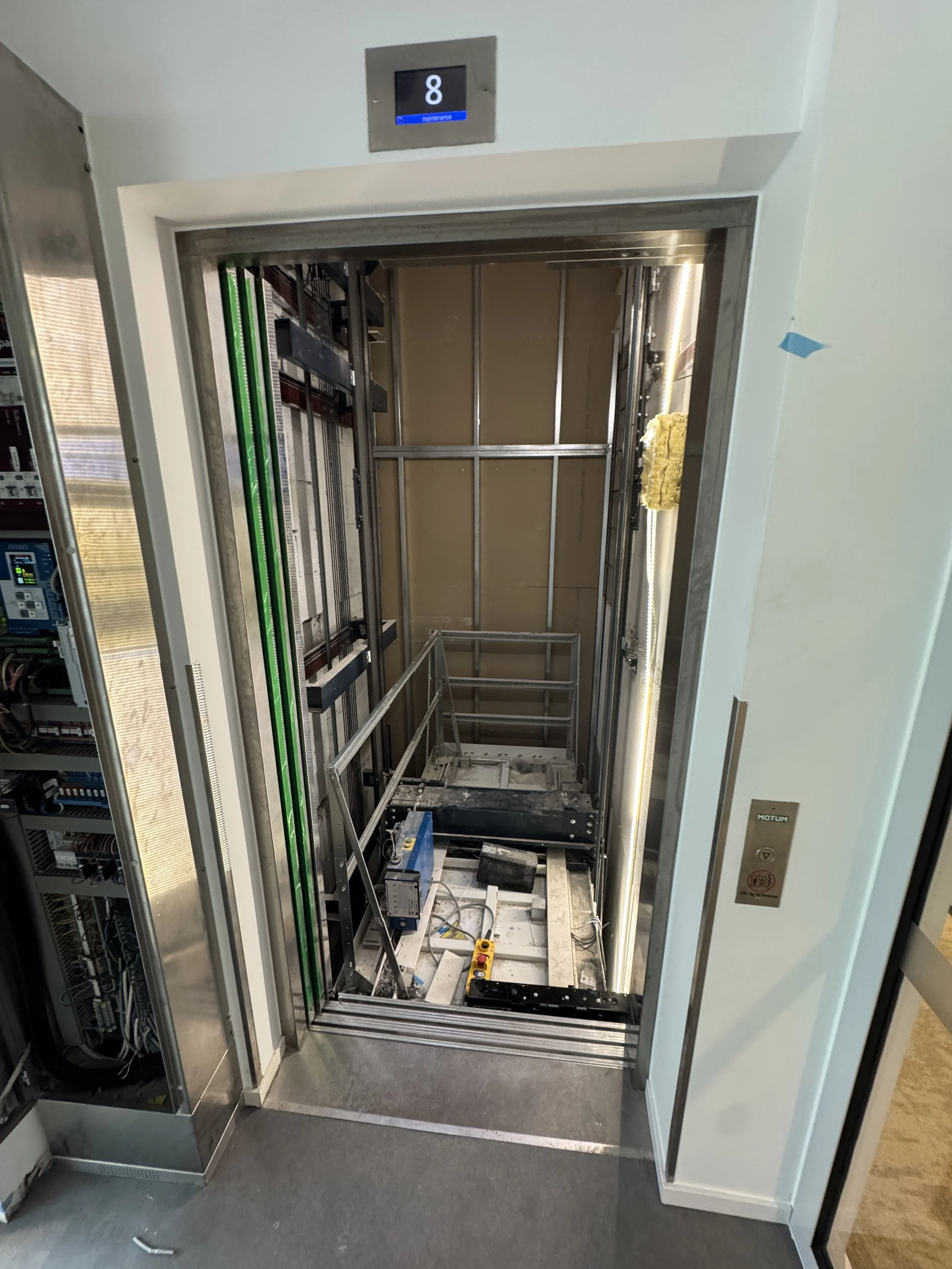 Ledig heiser i ferd med å bli installert, med maskineri og kontrollutstyr synlig.