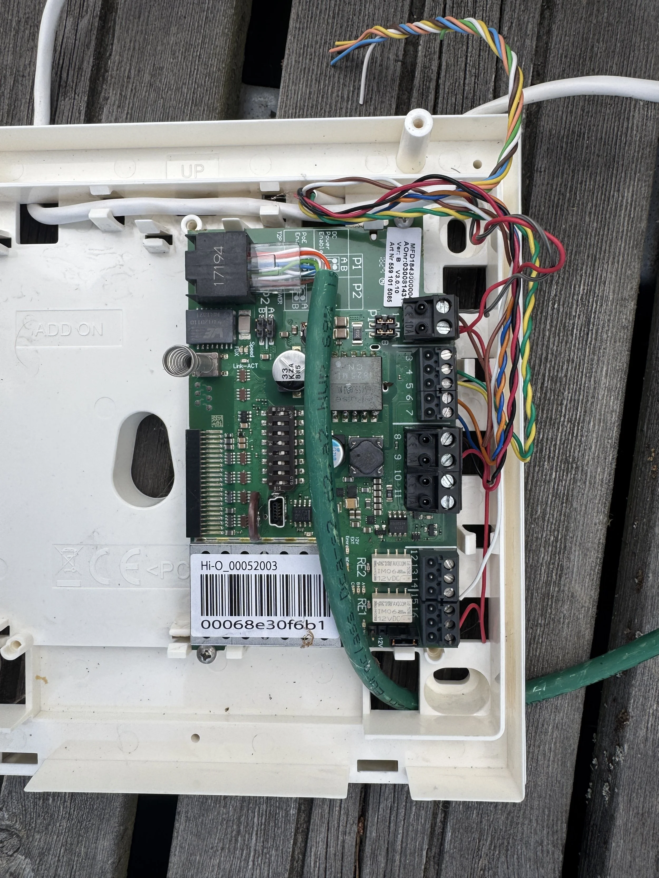 Inne i en åpen hvit elektronikkboks, som viser en grønn kretskort med flere tilkoblede ledninger og komponenter.