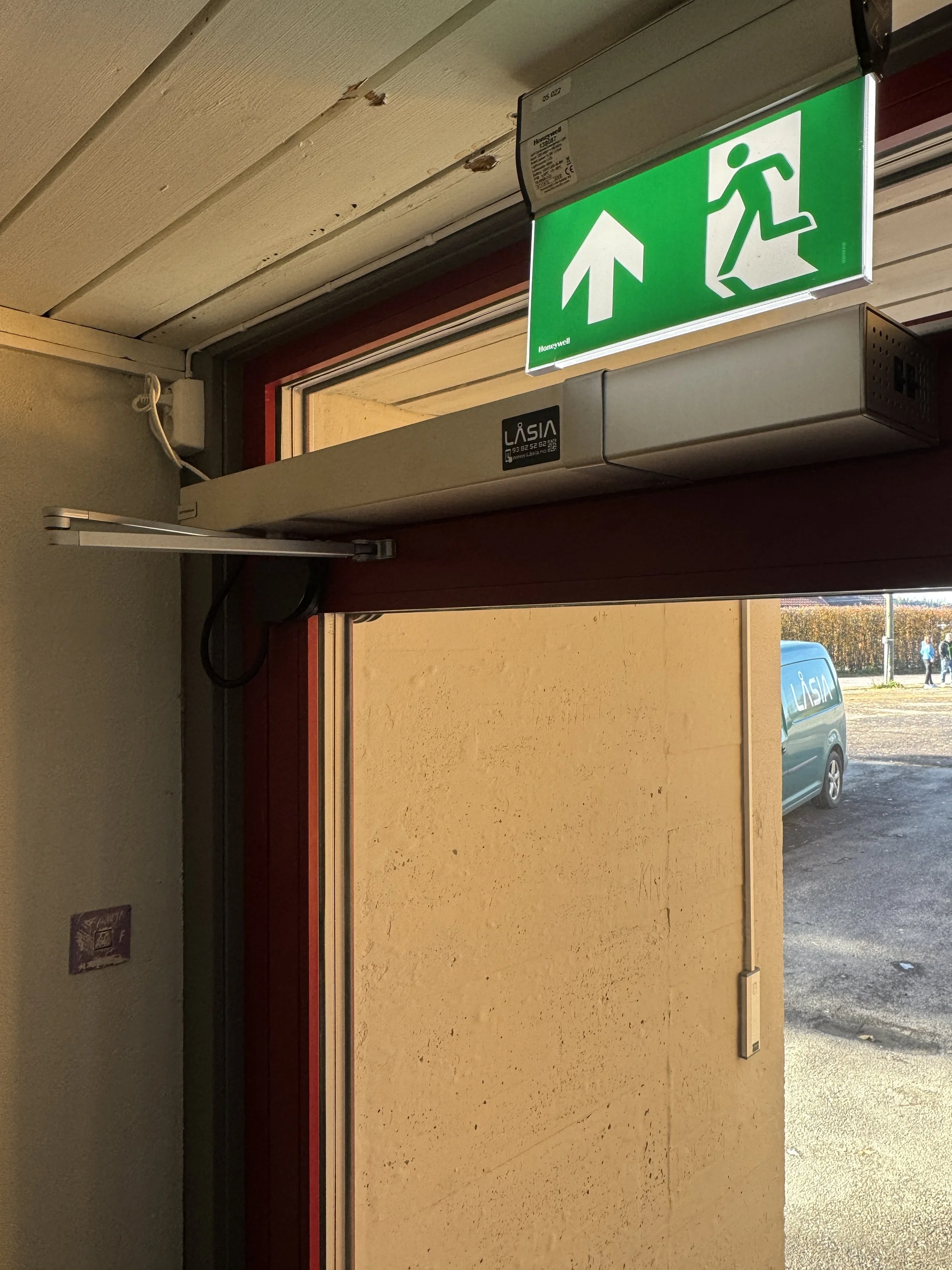 Evakueringsskilt som viser en person som går ut gjennom en nødutgang, og en pil som peker oppover.