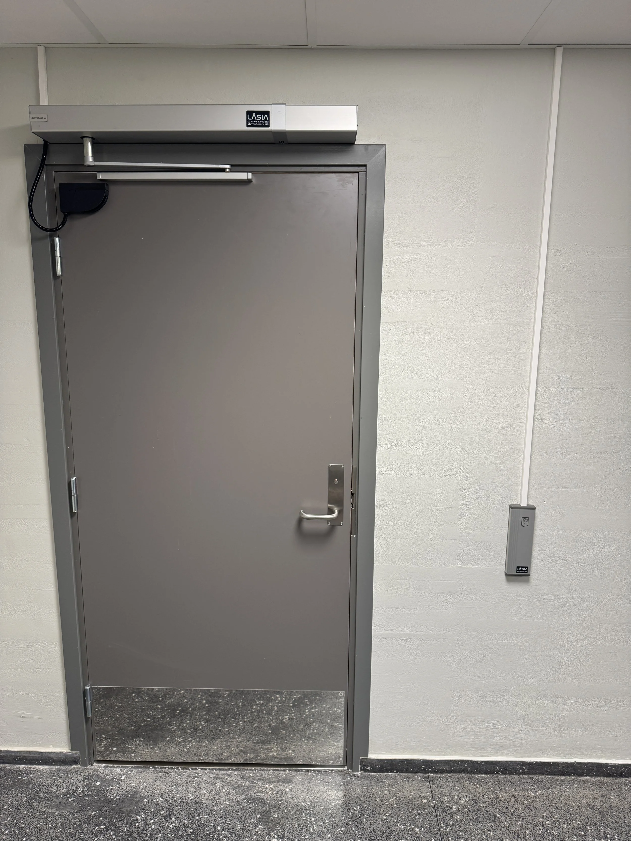 En grå industridør med overvåkningsutstyr montert over og til høyre for døren.