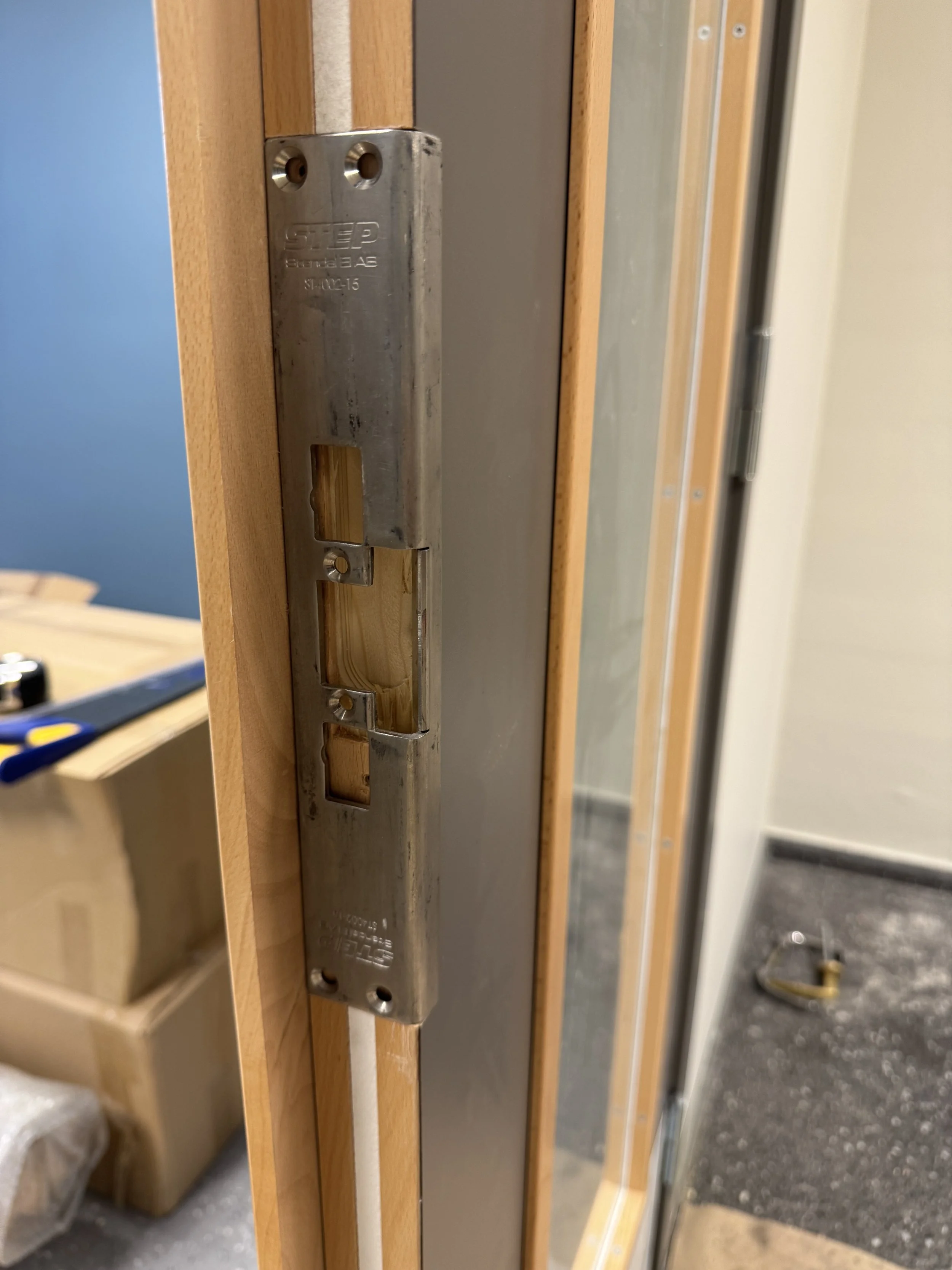 Dørterskel med metallplate og treverk, under montering, på byggeplass.