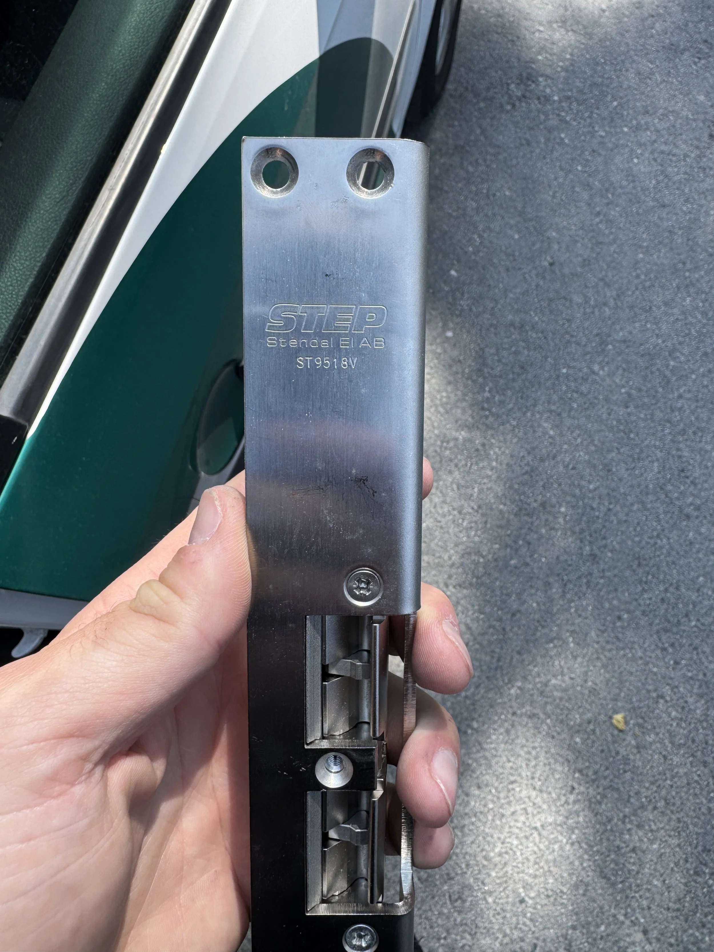 En hånd holder en metalstav med skruer og mekaniske deler, merket 'STEP Stengel LAB ST9518V'.