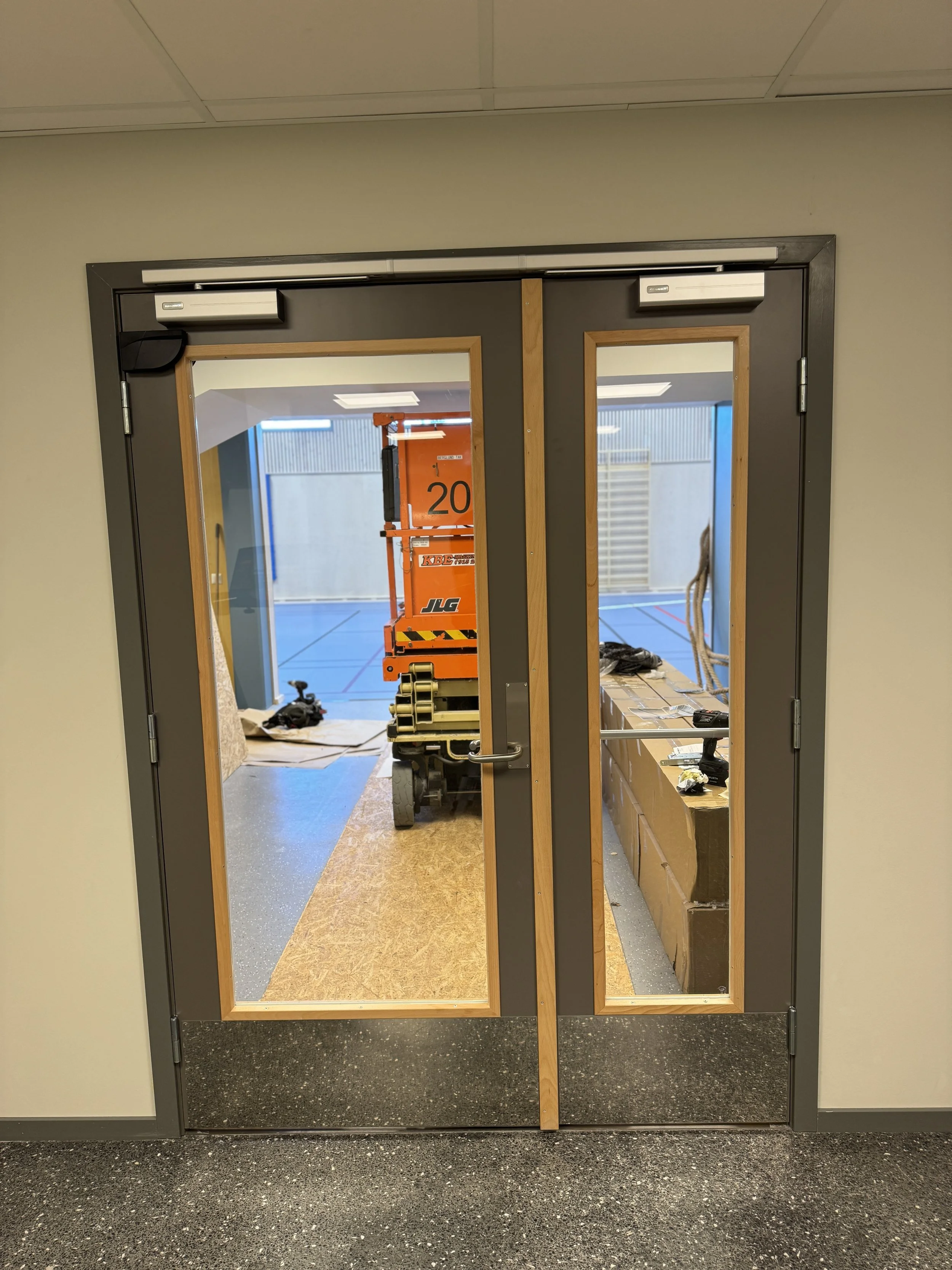 Interiør av en inngangsdør til et rom under konstruksjon, med synlige arbeidsverktøy og utstyr.