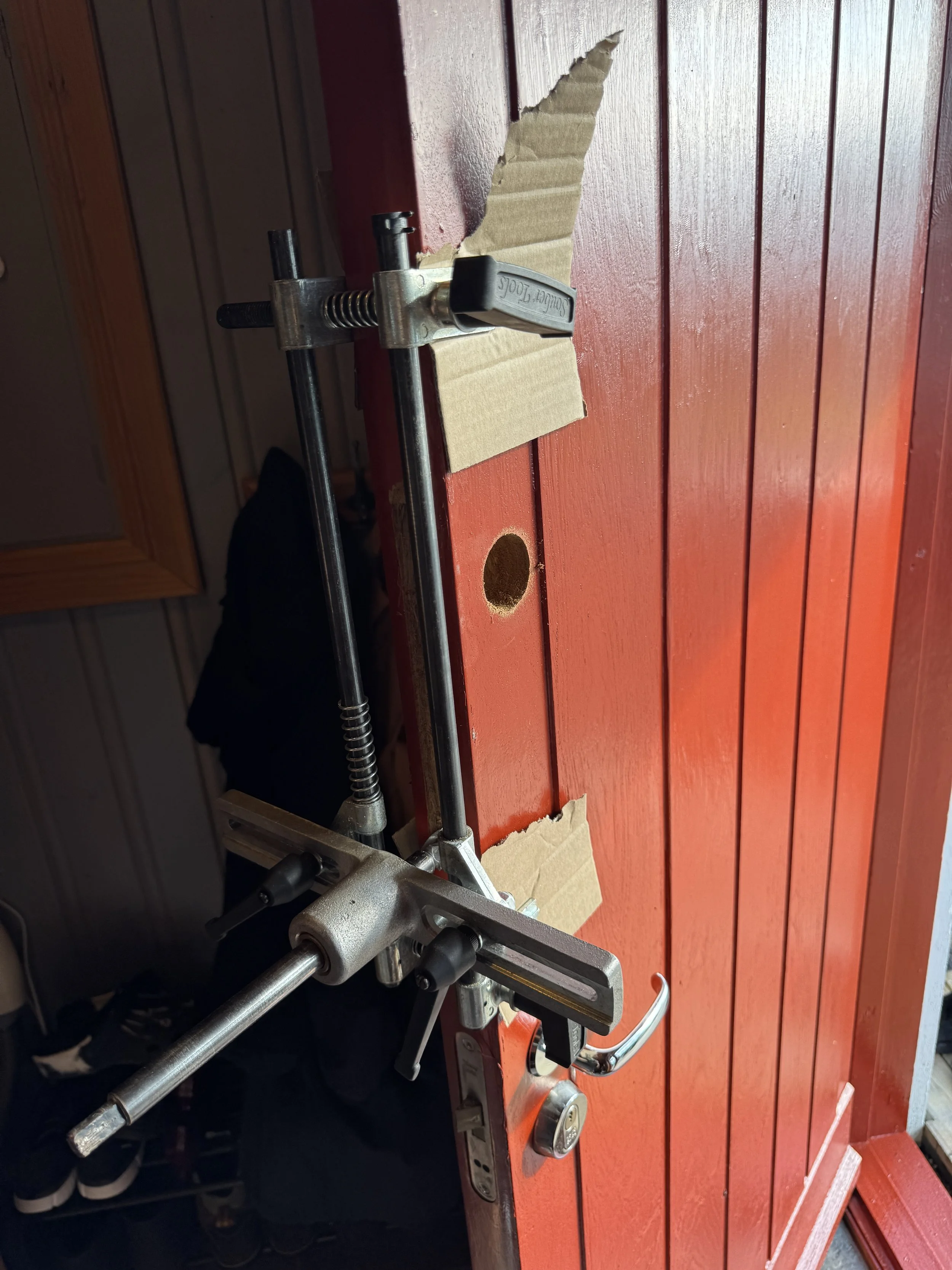 Bildet viser en kjøkkenbenk med en vinkeljernklemme festet til et bord, og det er satt inn kartongbiter for å beskytte bordet under reparasjonsarbeid.