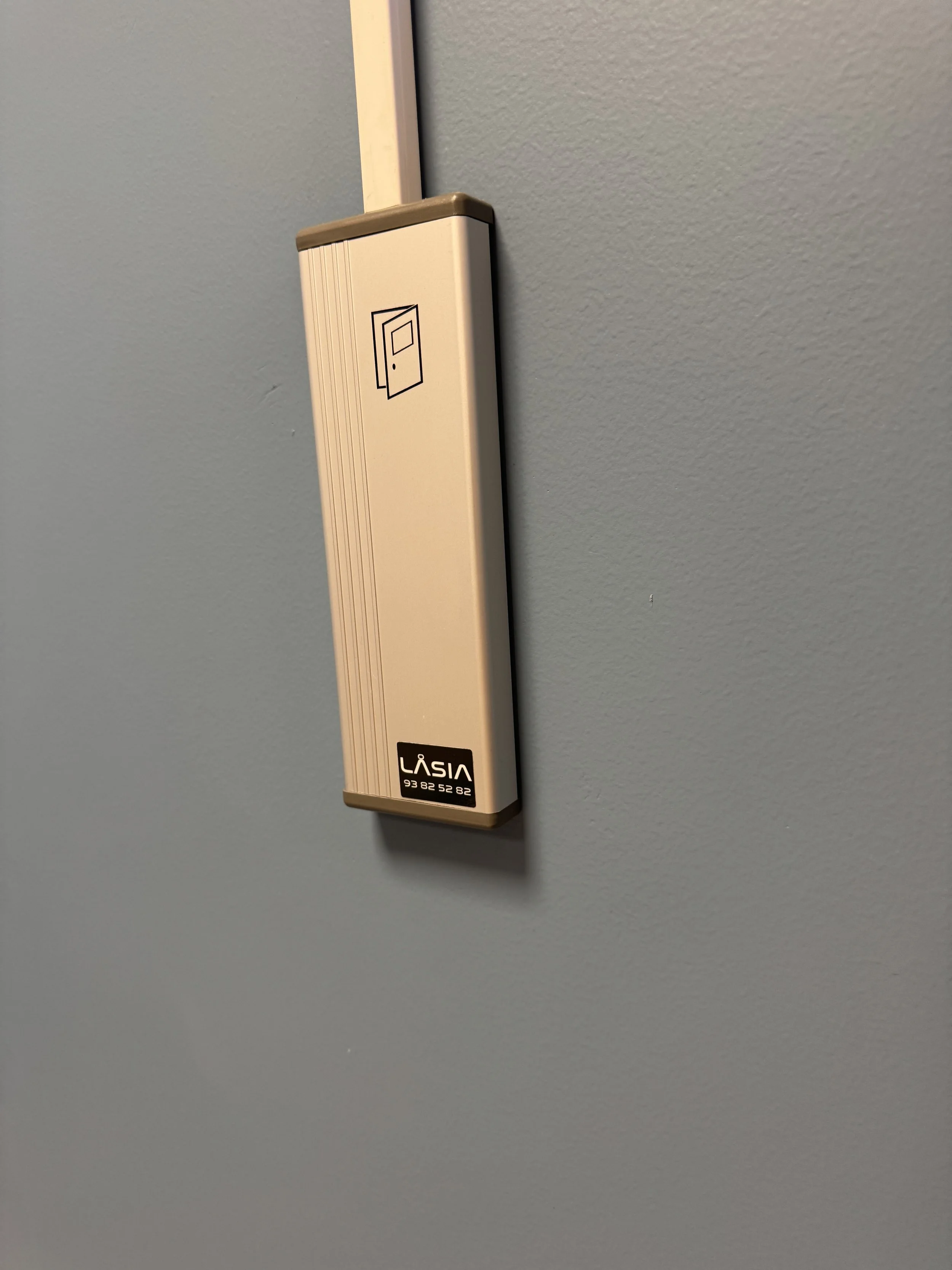 Et intercom- boks montert på en blå vegg med en liten etikett som sier 'Låsia'.