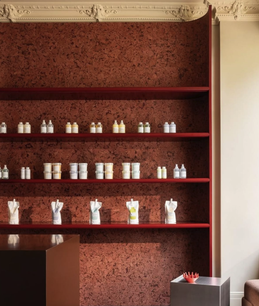 salon de coiffure avec mur en liège rosé, produits de salon de coiffure sur les étagères