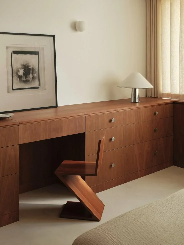 meuble sur lesure en bois avec chaise zigzag Rietveld, lampe Tacchini, mur crème et sol moquette beige