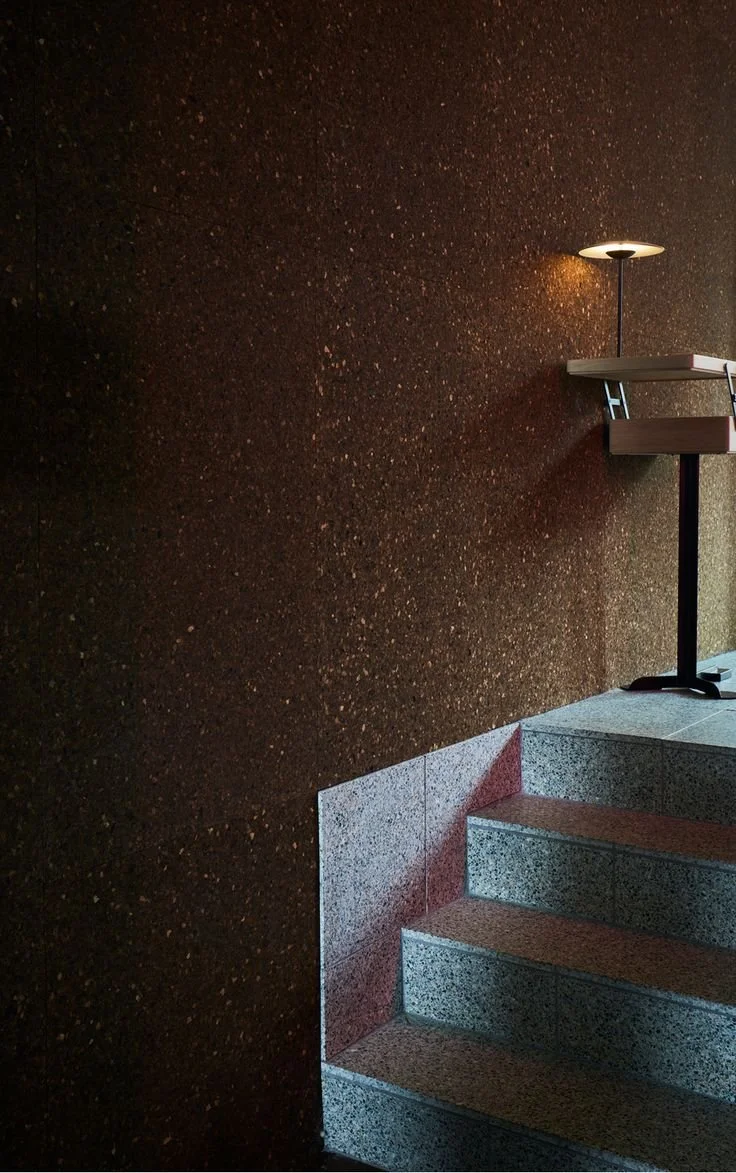 murs recouverts de liège avec marches en pierre , petit bureau en haut des marches avec lampe dessus