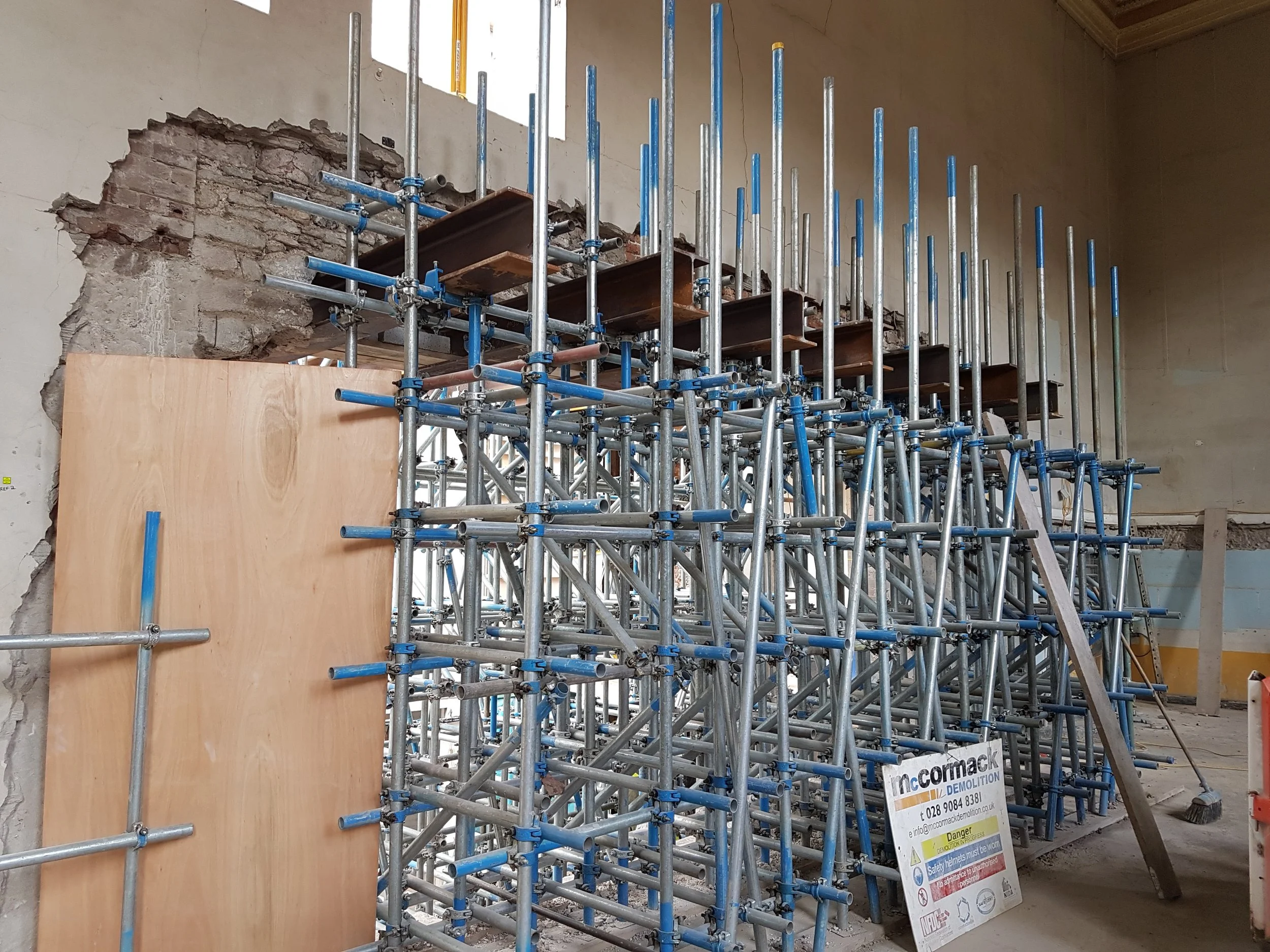 Construction scaffolding and partially demolished wall in a building under renovation.