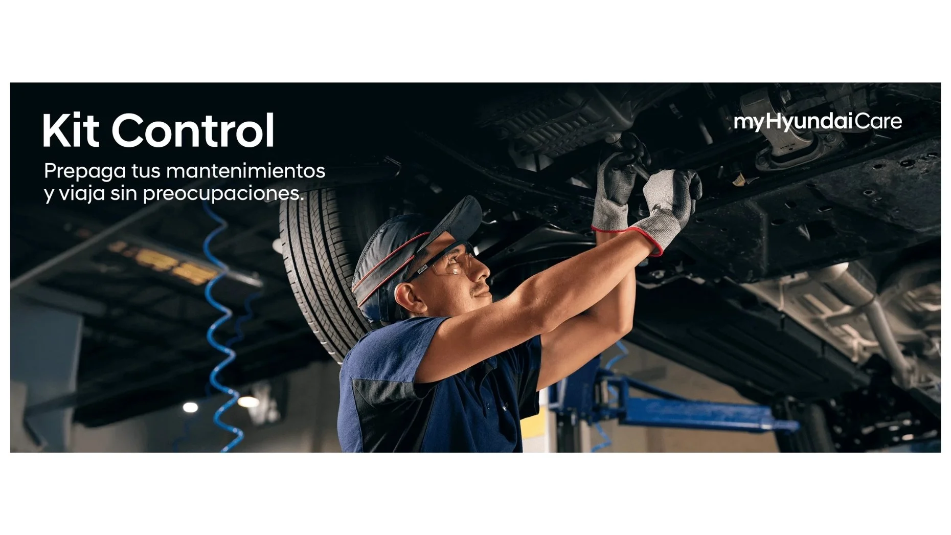 Un mecánico trabajando debajo de un automóvil levantado en un taller, revisando el motor.