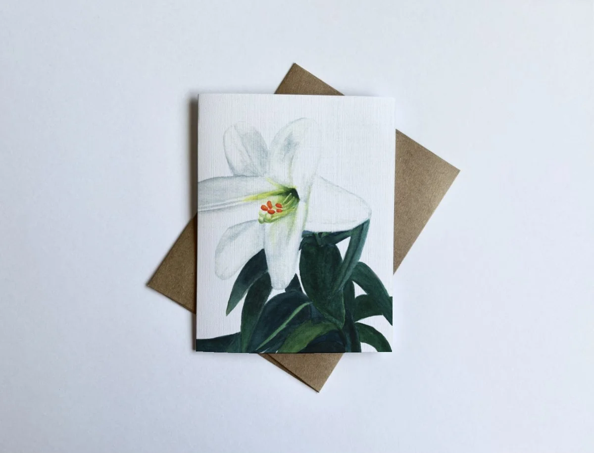 Watercolor Easter lily art on linen-textured cardstock, featuring soft white petals and green leaves.