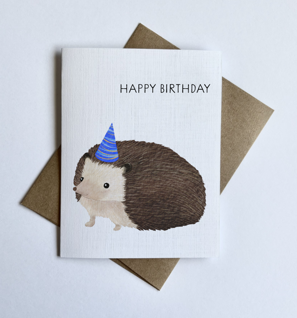 Closeup of a cute hedgehog birthday card with party hat illustration, whimsical animal birthday greeting card