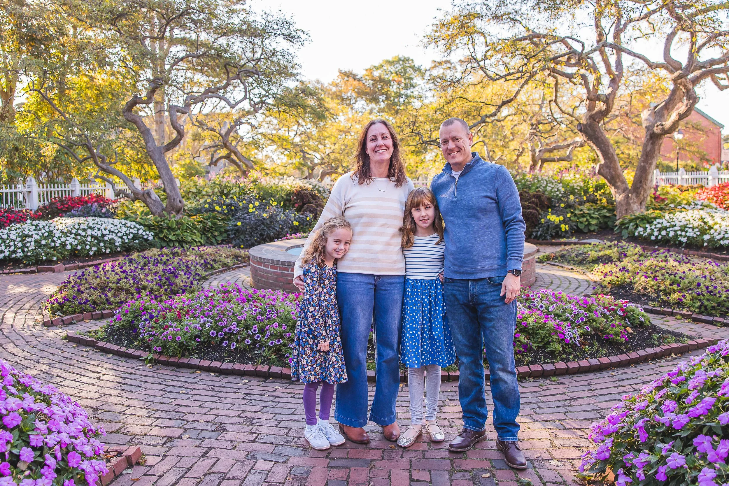 family of four at an early morning fall session in prescott park gardens infront of the fountains