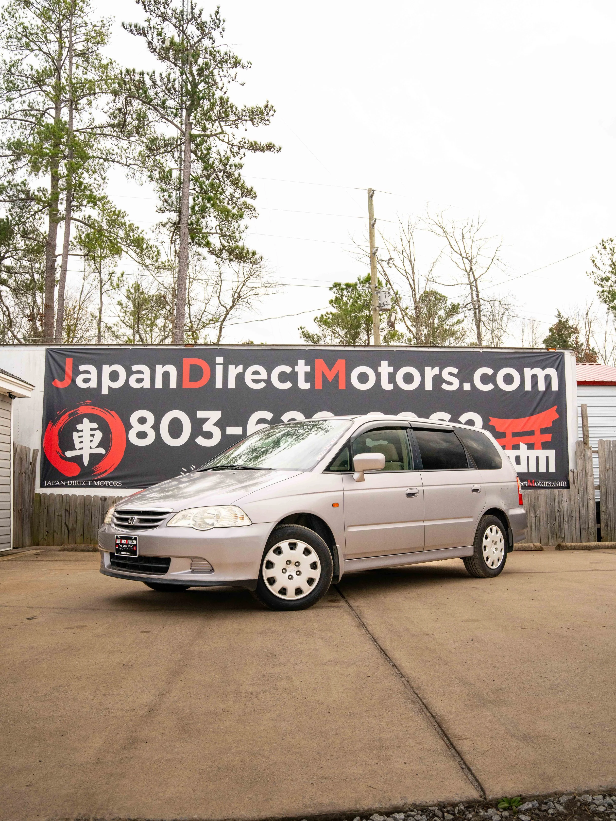 Right Hand Drive Honda Odyssey parked in front of a Japan Direct Motors sign