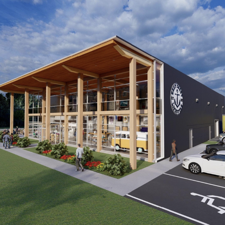 Modern building with a black exterior and a large anchor logo, extensive glass walls, surrounded by green lawns and parking lot, under a cloudy sky.