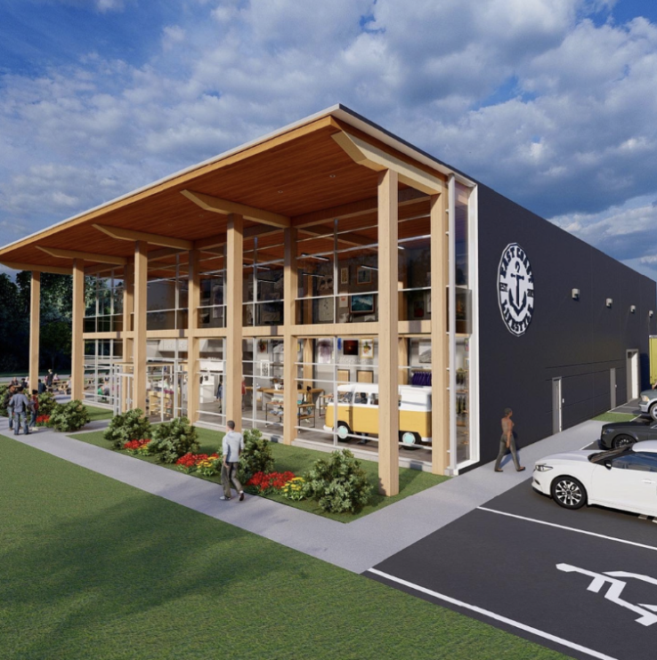 Rendering of a modern two-story building with large glass windows, wooden beams, and an overhang. A logo with an anchor is on the black exterior wall. People walk near the building, which has a parking lot and landscaped area with bushes and flowers.