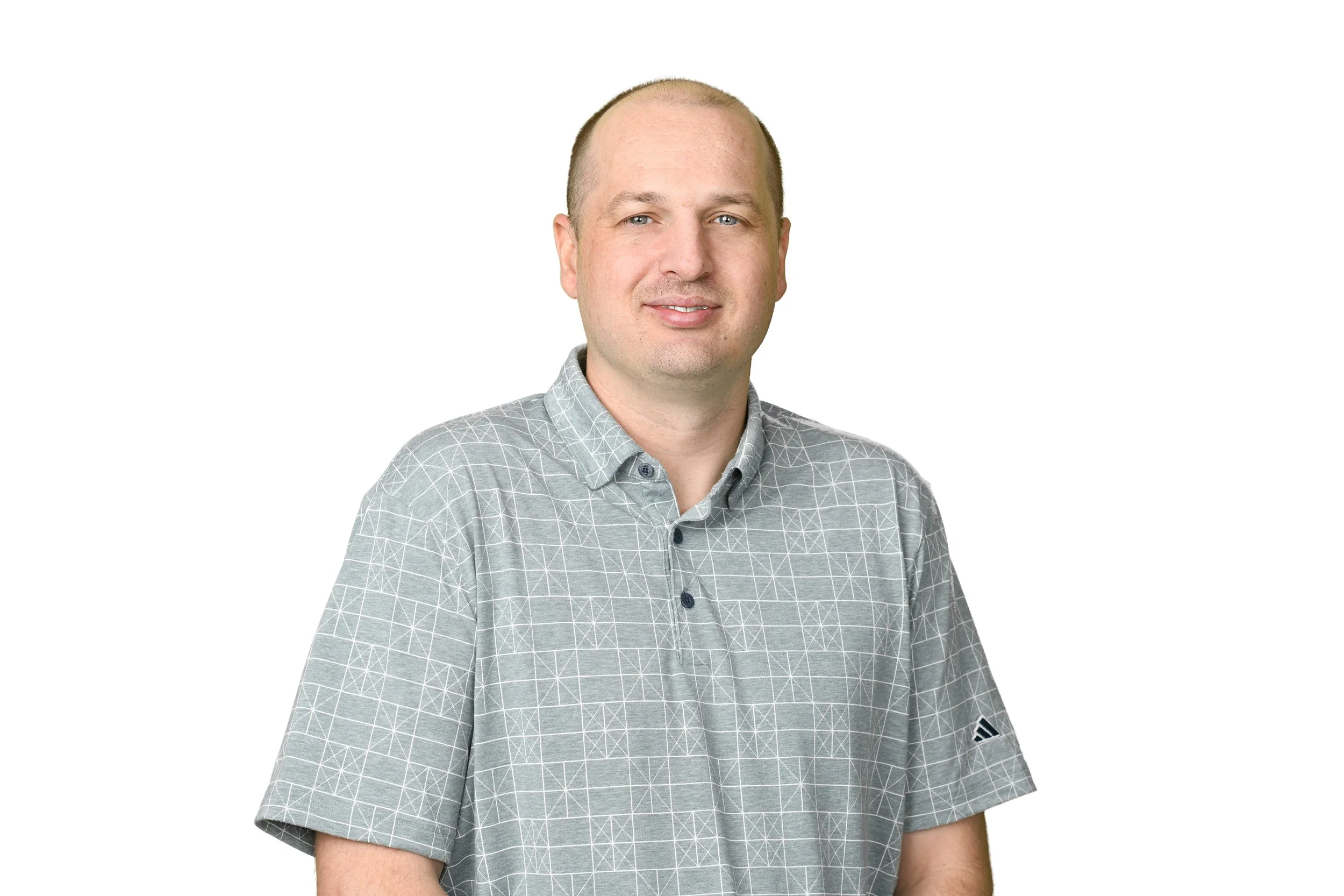 A man with short hair wearing a gray checkered polo shirt, smiling against a white background.