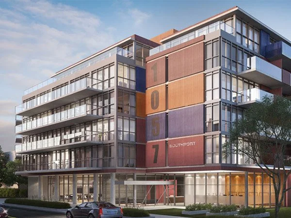 Modern multi-story building made from stacked shipping containers with large glass windows, located in an urban area.