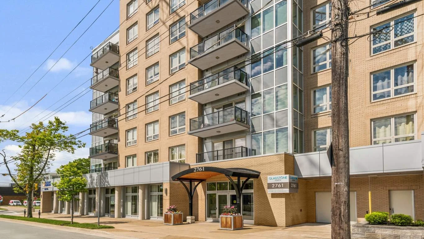 Exterior view of a modern multi-story apartment building with balconies, large windows, and a covered entrance, located on Gladstone Street.
