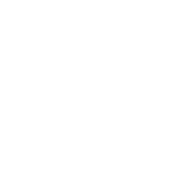 Person sitting on a table, holding a dish with a circular pattern, with a bottle nearby.