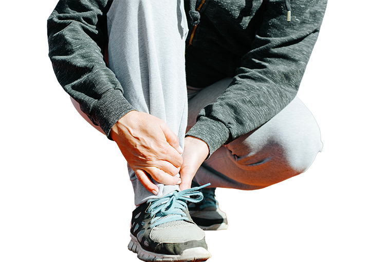 A person helping another person tie their shoelaces on a running track.