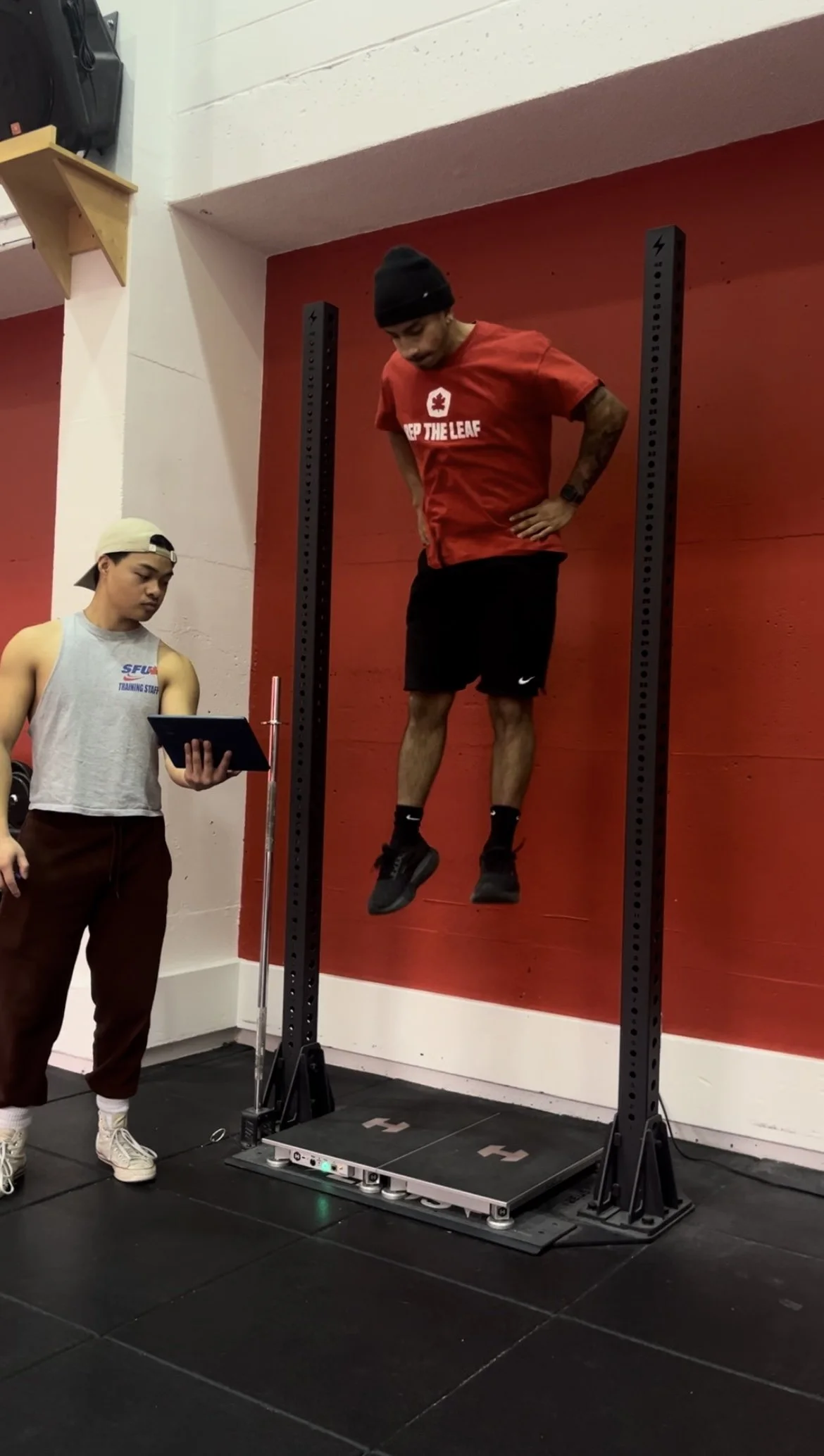 Person performing a counter movement jump (CMJ) test on a force plates with an intern assistance.