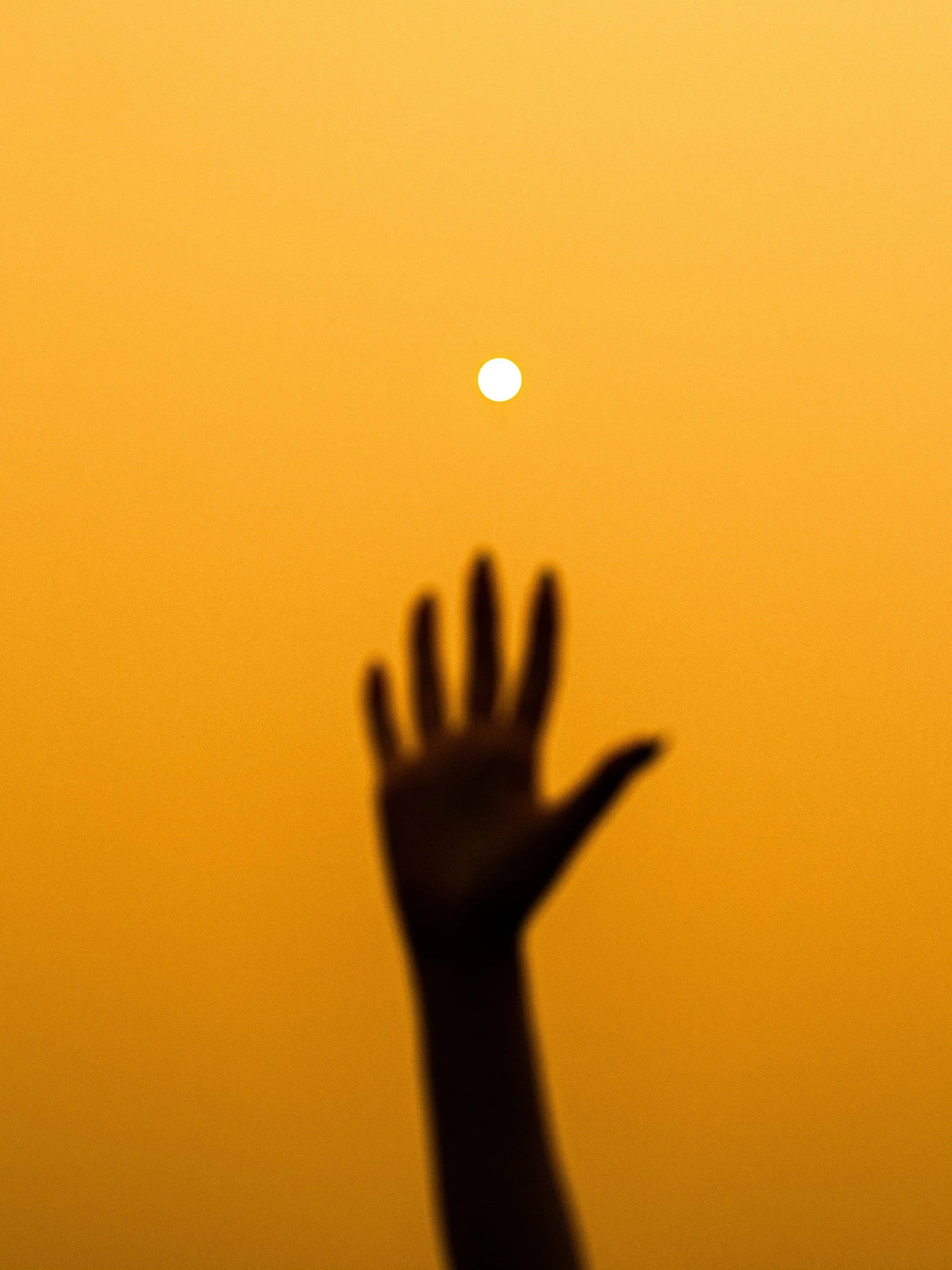 hand reaching for sun on yellow background