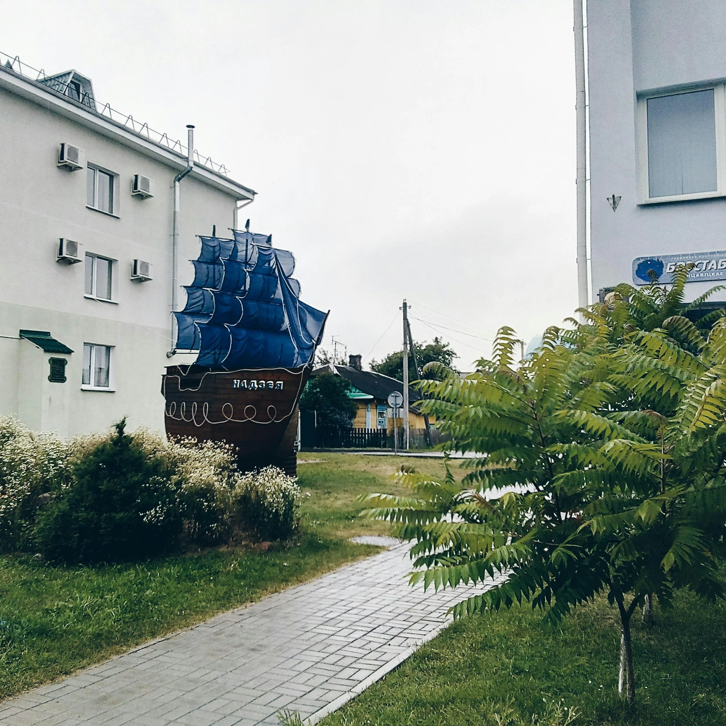 A tractor snow plow clearing snow from a driveway at night with houses in the background.