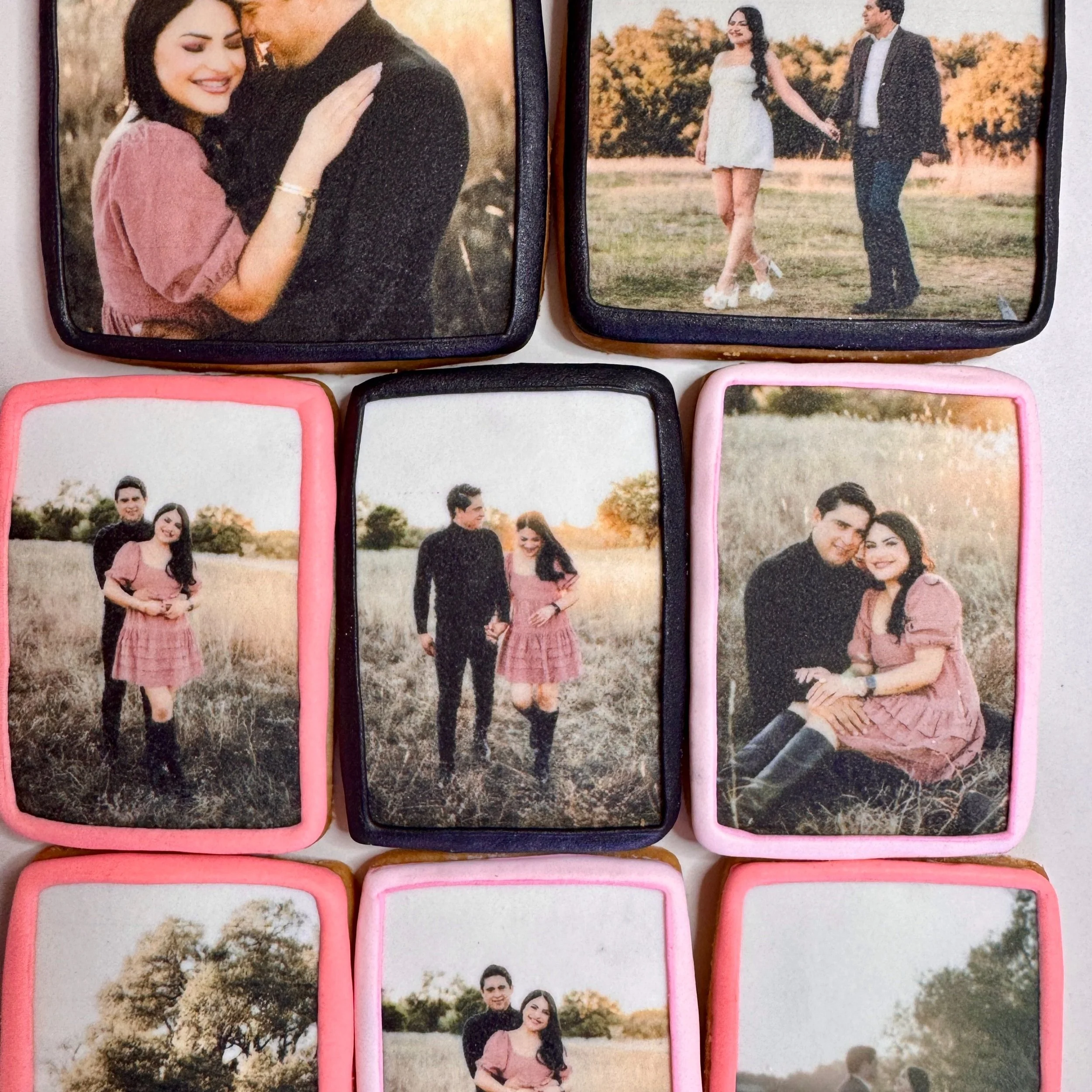 A collection of nine decorated cookies featuring photographs of a young couple in various outdoor settings, with some cookies framed in pink or black icing.