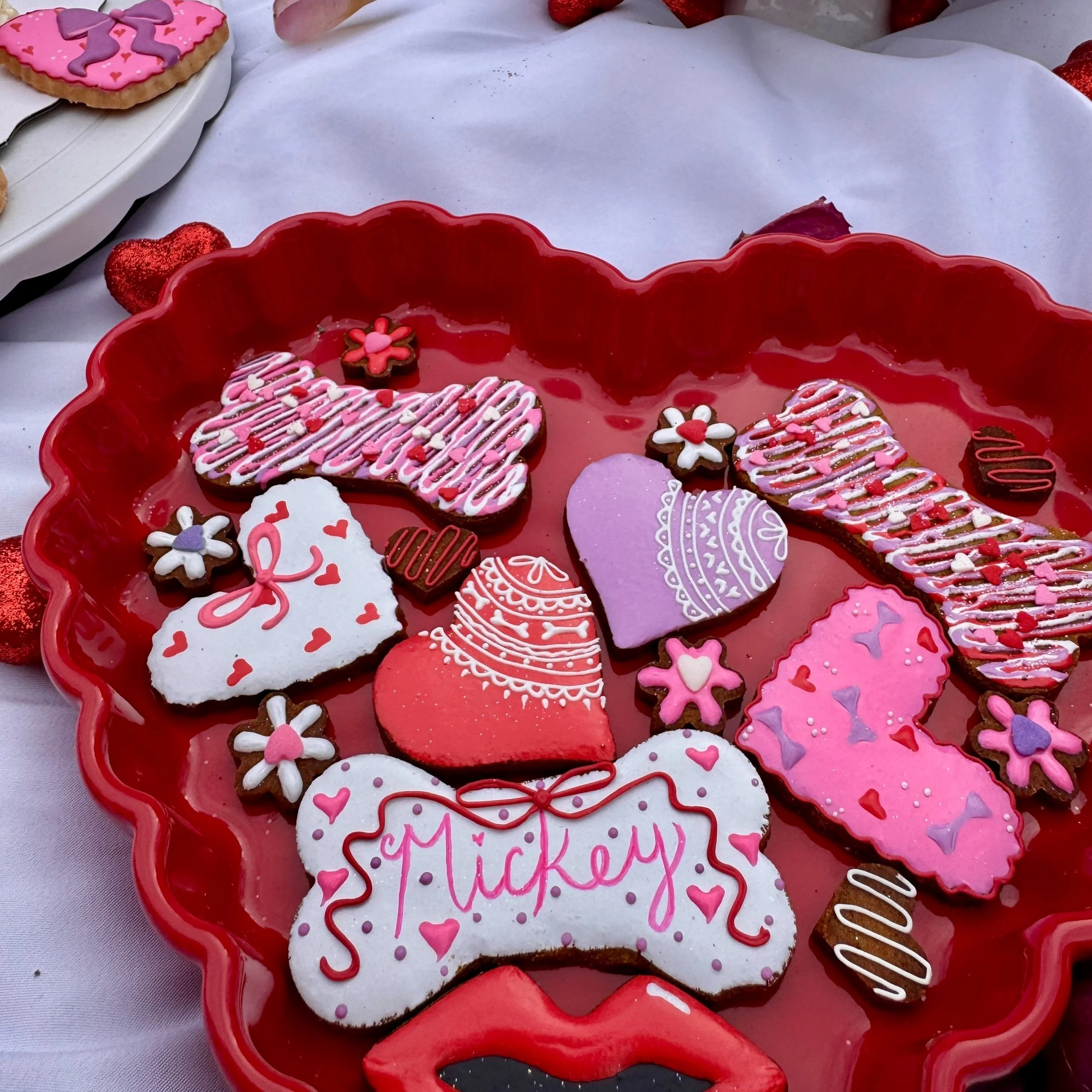 Valentine's Day decorated cookies on a red tray, including Mickey Mouse shaped cookie, hearts, roses, and lip shapes with pink, red, purple, and white icing.