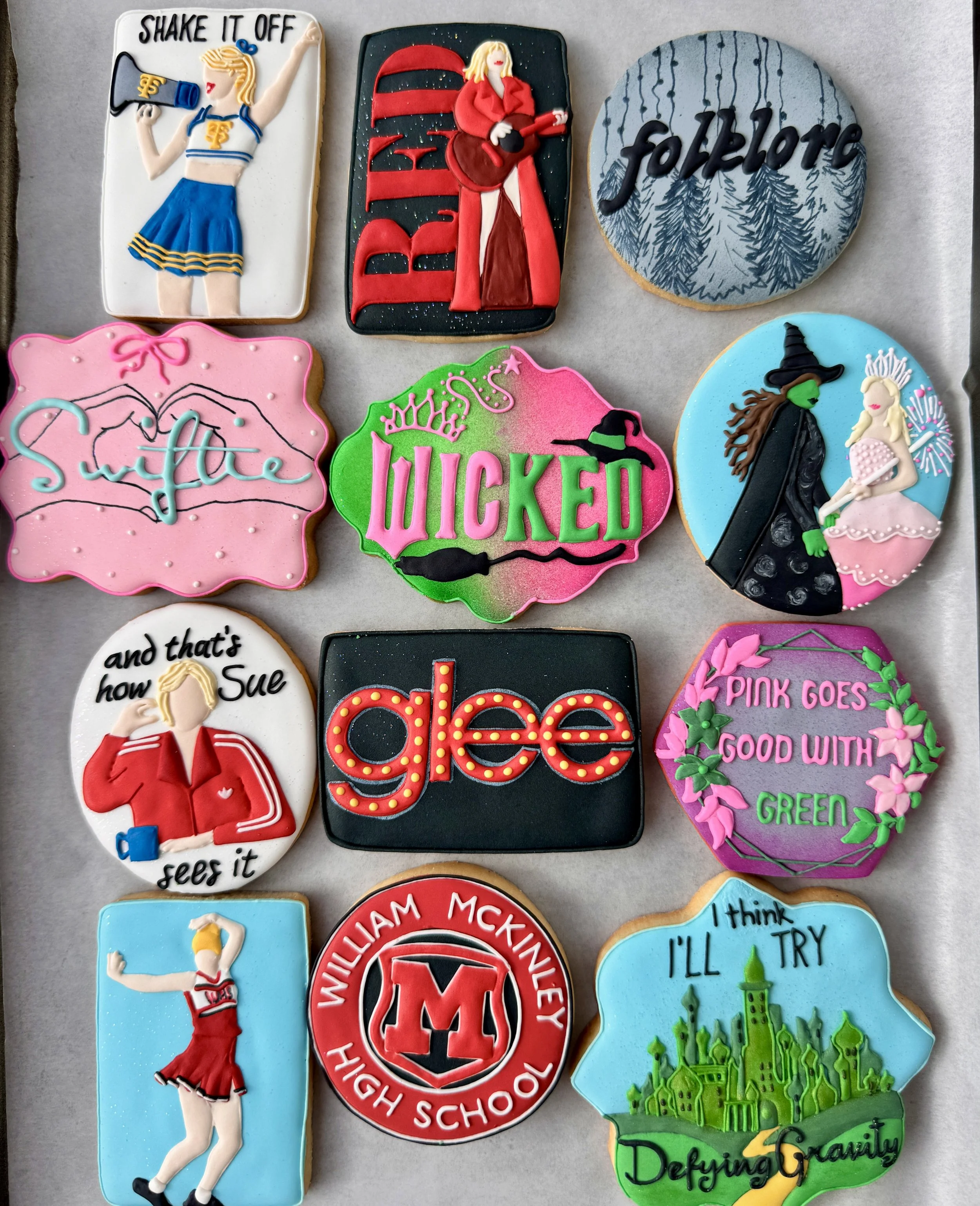 Collection of decorated cookies with various themes and designs, including a cheerleader, musicians, witches, and motivational messages.