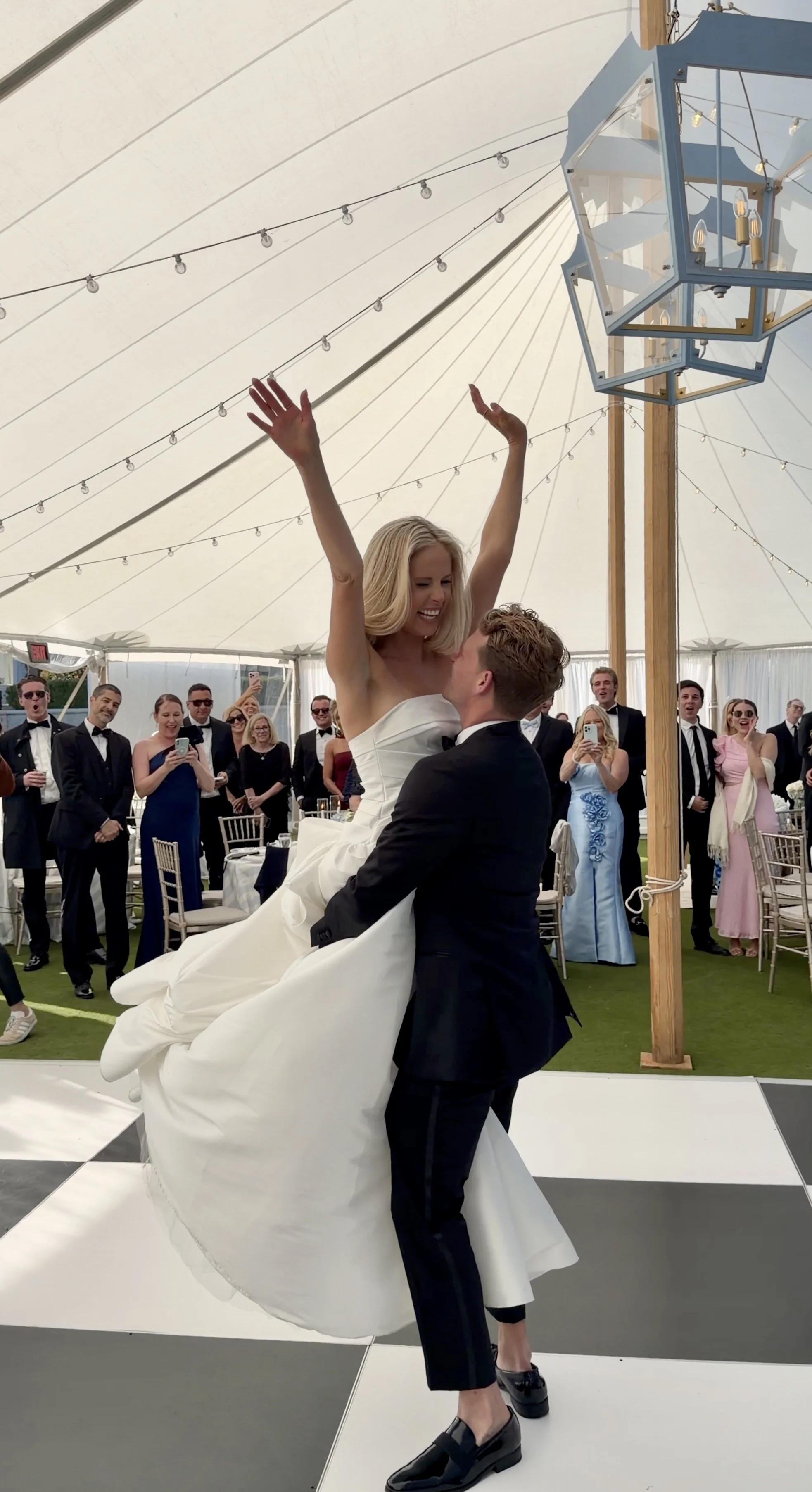 A bride being lifted by a groom during a wedding reception under a large tent by wilmington content co - content creator in north carolina at a luxury wedding
