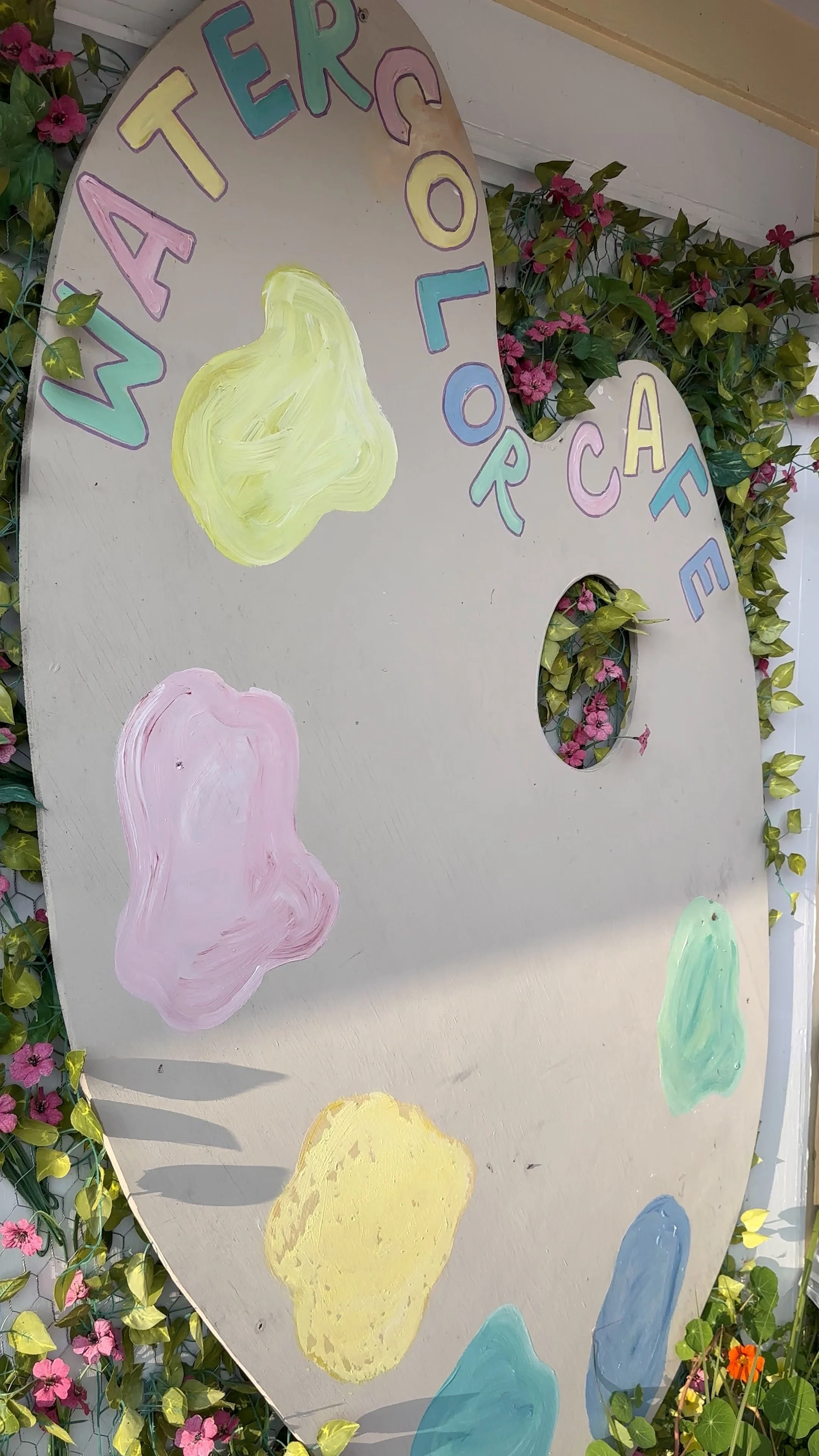 Colorful chalk-drawn Easter-themed decorations on a white board, including pastel-colored eggs and a yellow chick, surrounded by pink and green flower vines.