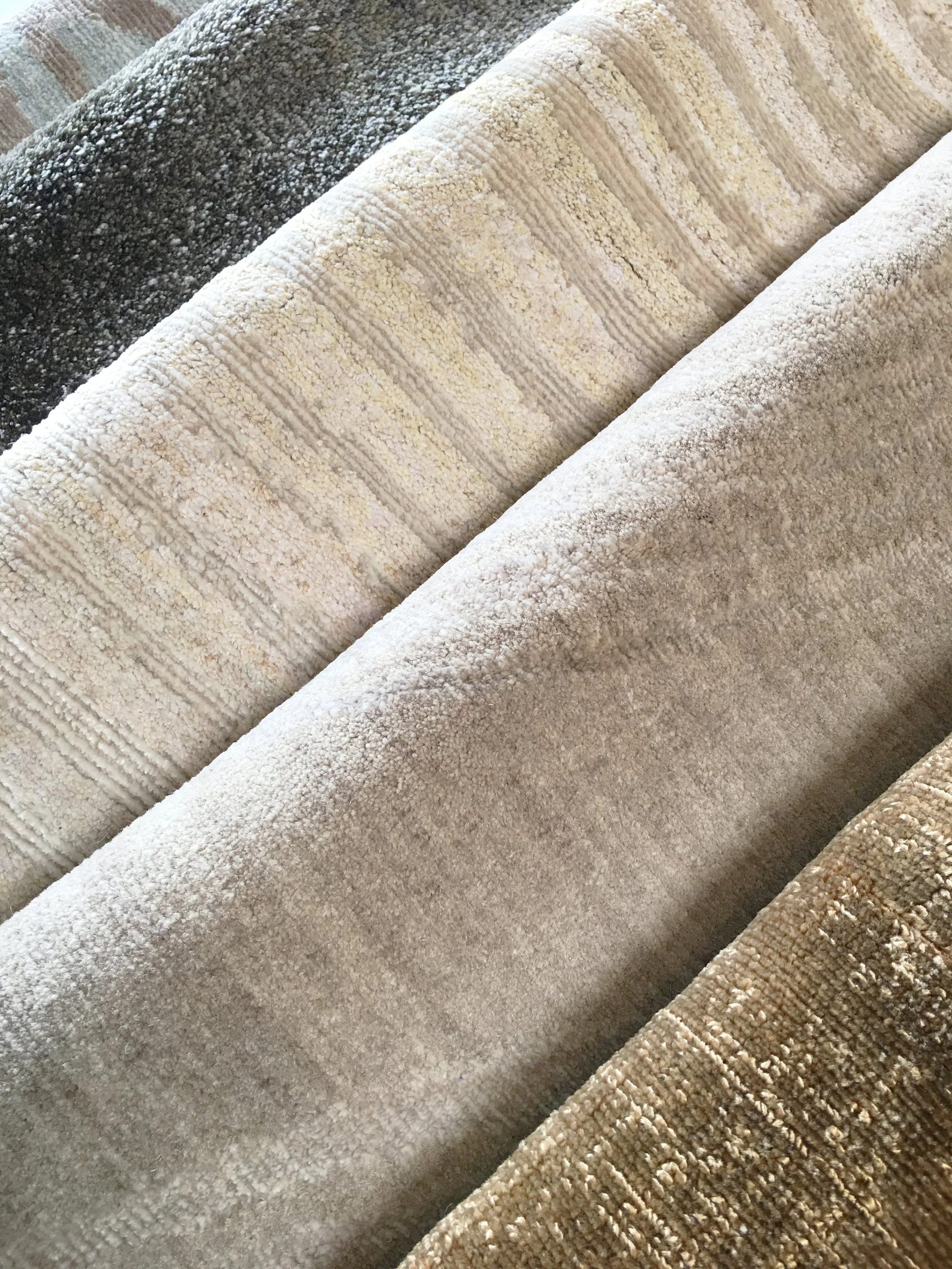 Layers of fine area rugs, stacked neatly with neutral patterns