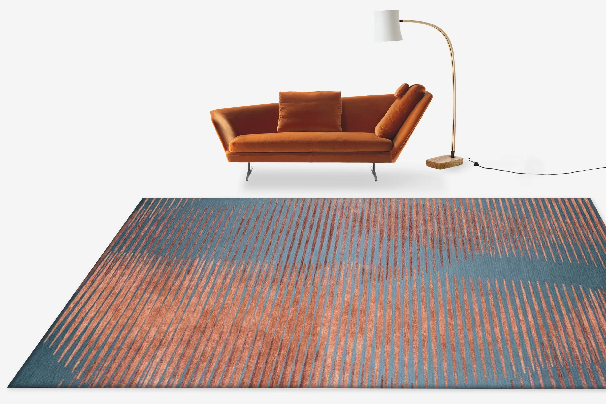 A modern orange velvet sofa with pillows, a tall white floor lamp with a curved brass arm and wooden base, and a blue and orange striped area rug on a white background.