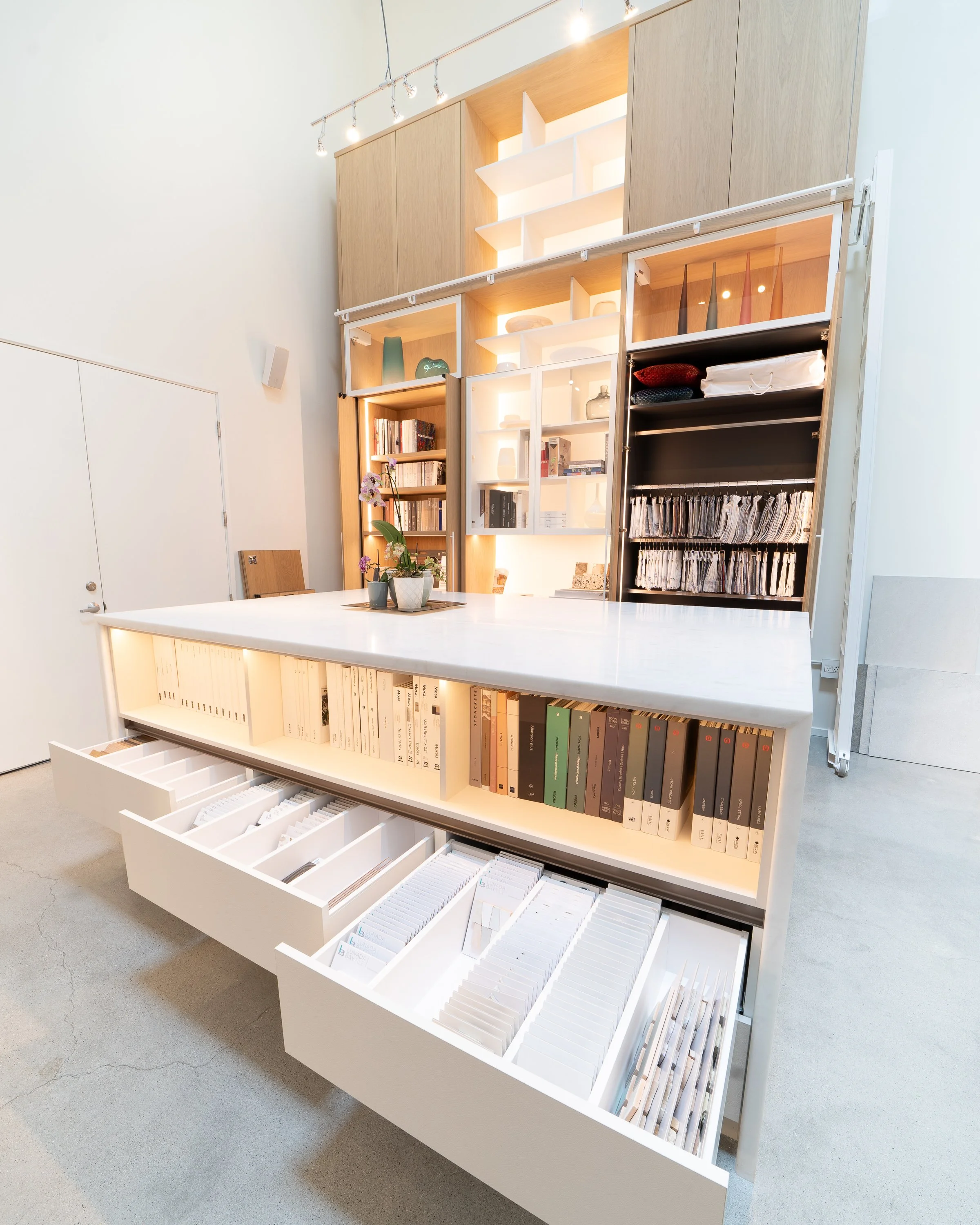 Modern open bookshelf with books, decorative items, and storage drawers in a bright room.