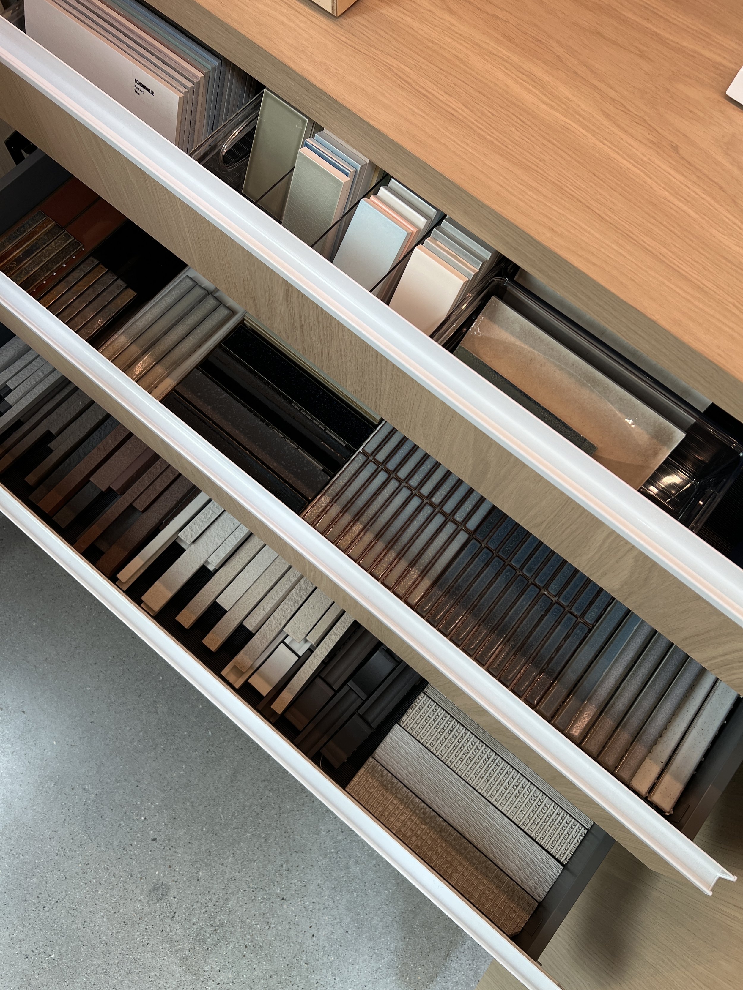 Drawers filled with various samples of tile, stone, or laminate in different colors and patterns.