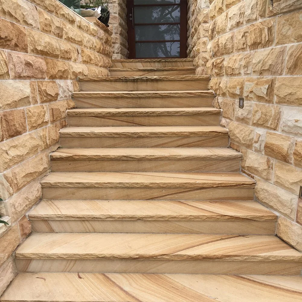 Stone stairs leading up to a door, with stone walls on both sides.