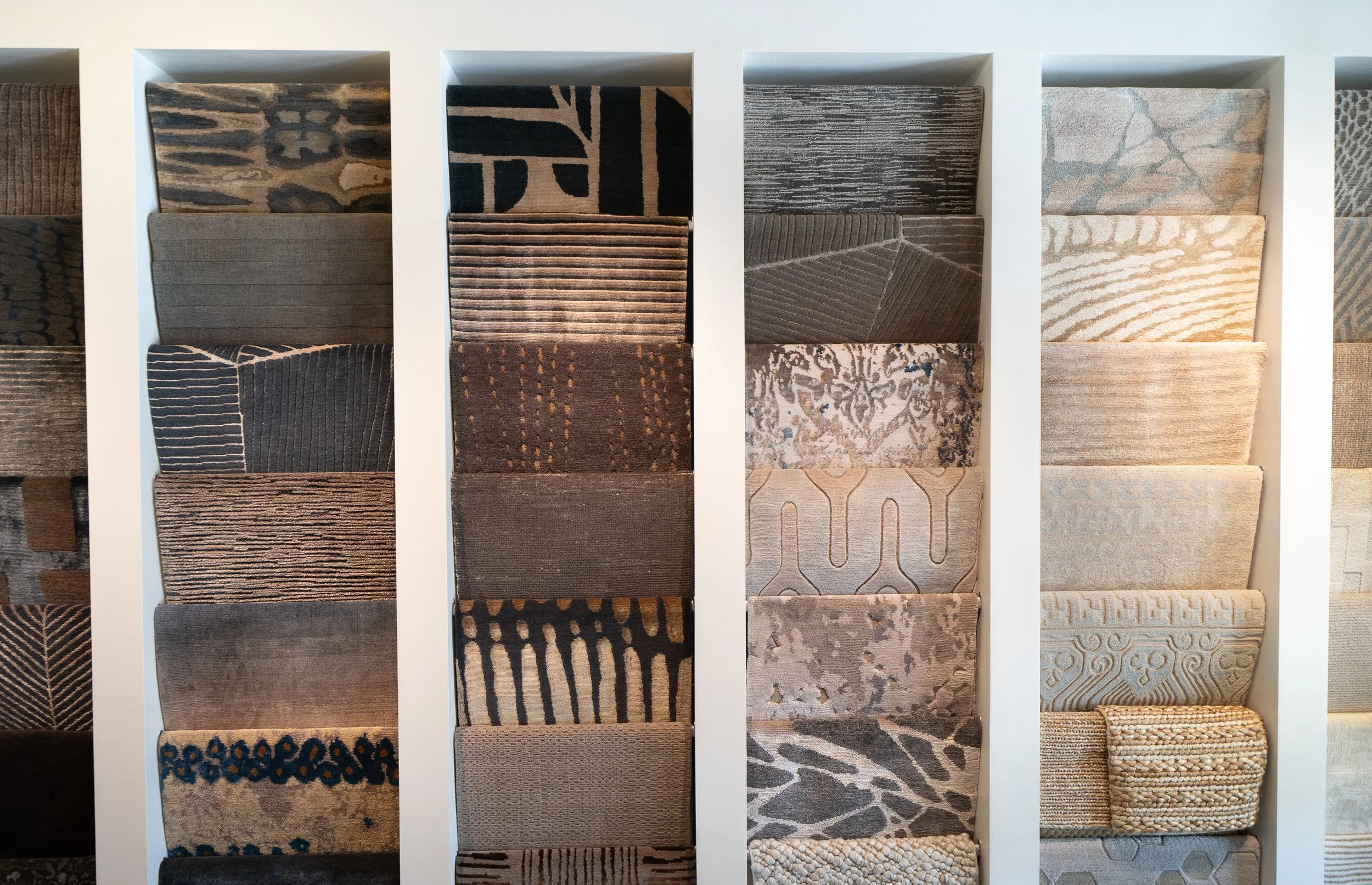 Display of various carpet samples arranged in vertical columns, showcasing different textures and patterns.
