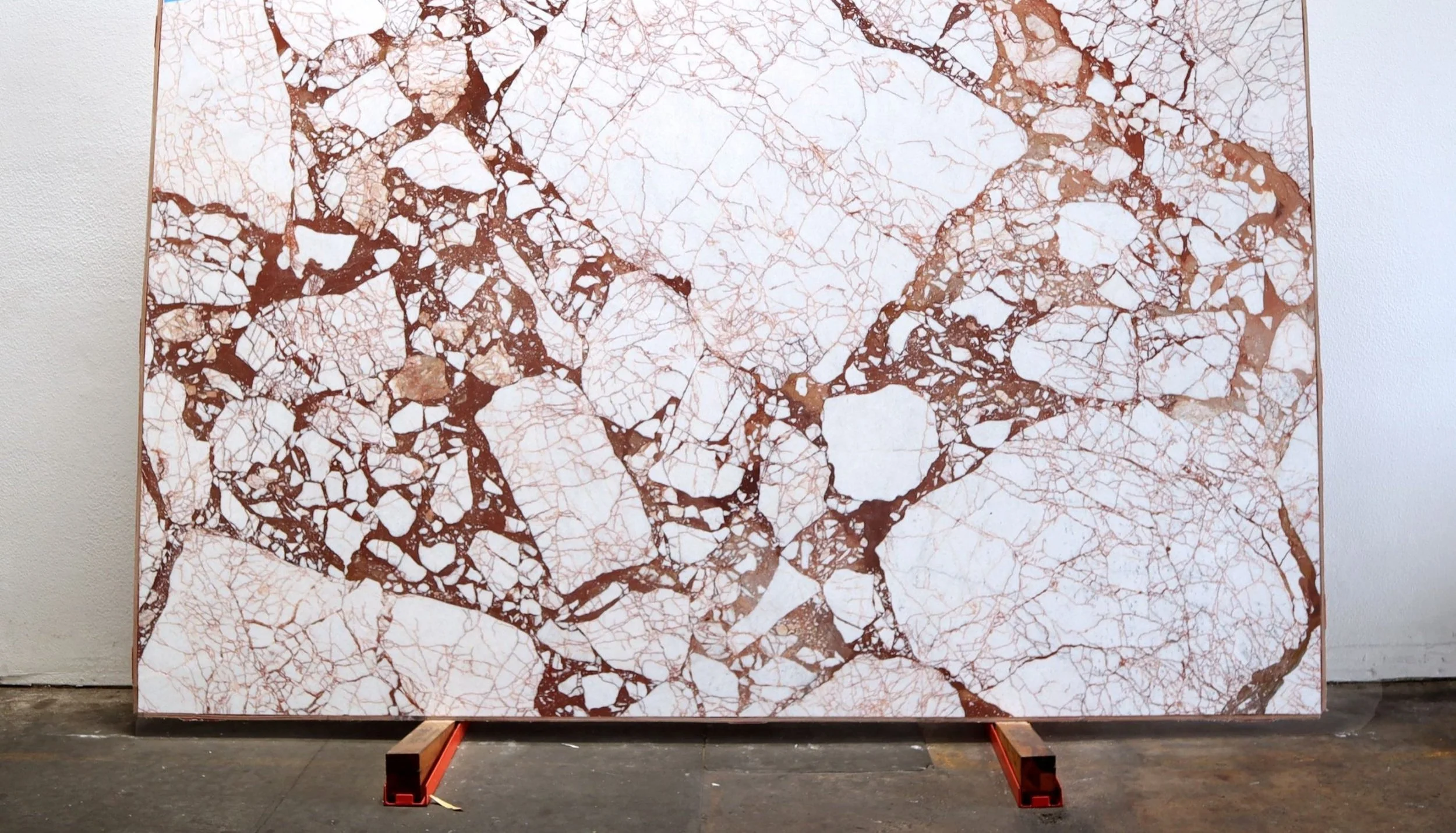 Large slab of white marble with intricate brown veining, supported by wooden and metal stands.