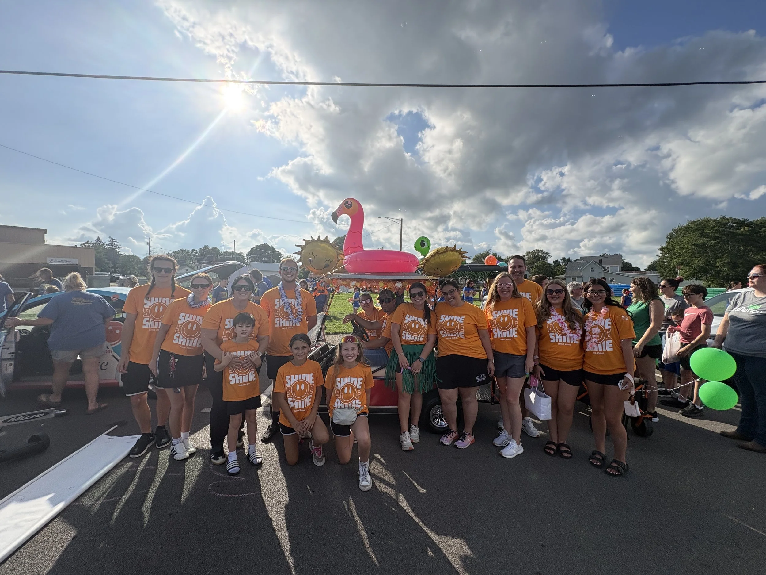 Full Shine Ortho Studio team in matching orange shirts posing for group photo at Henry County Parade event
