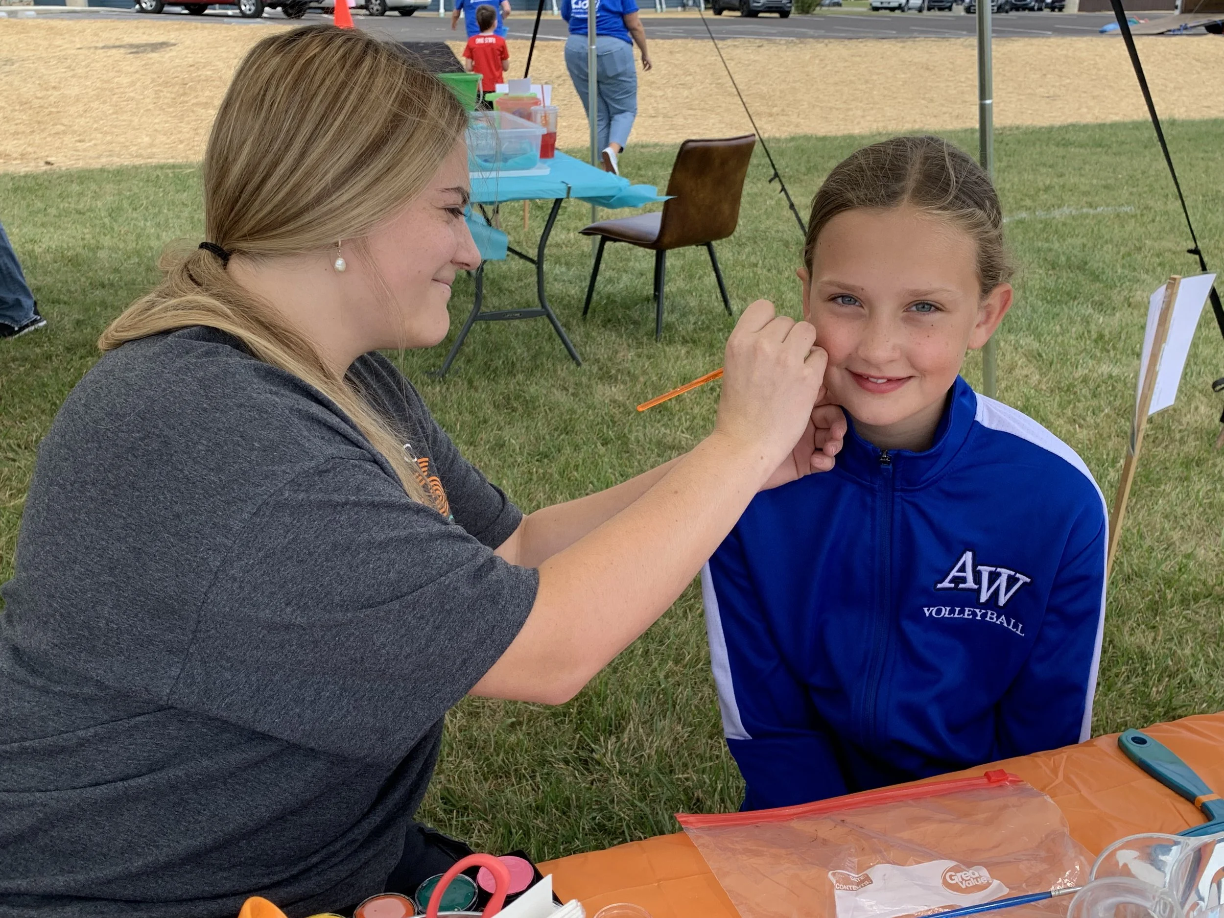 Shine Ortho Studio team member painting a child’s face at the open house community event.