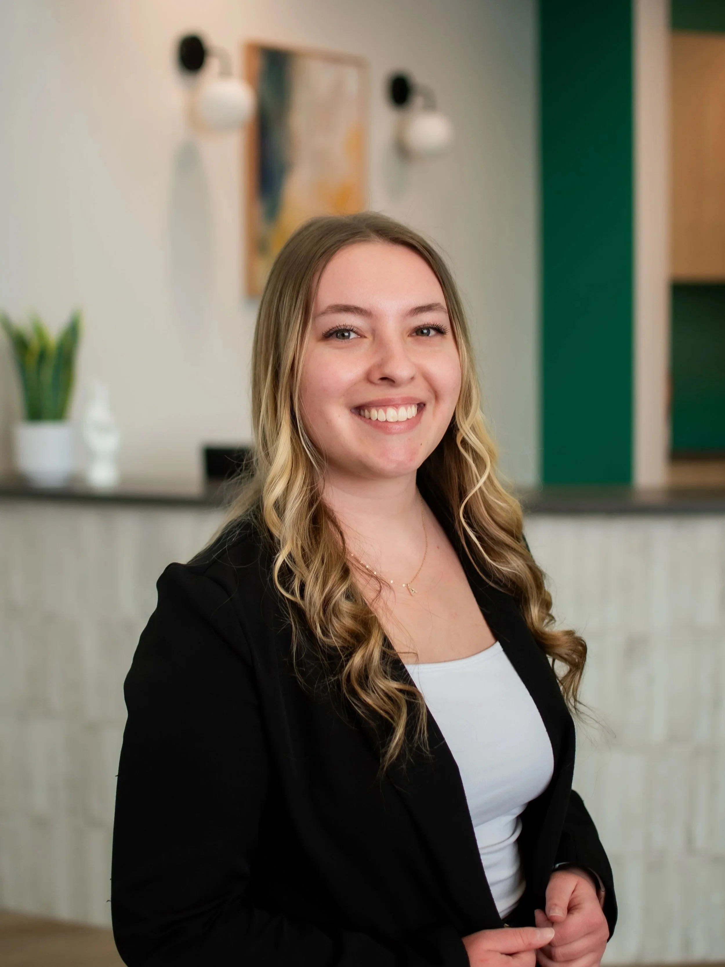 Adri Thompson, patient concierge at Shine Ortho Studio, standing and smiling in the office