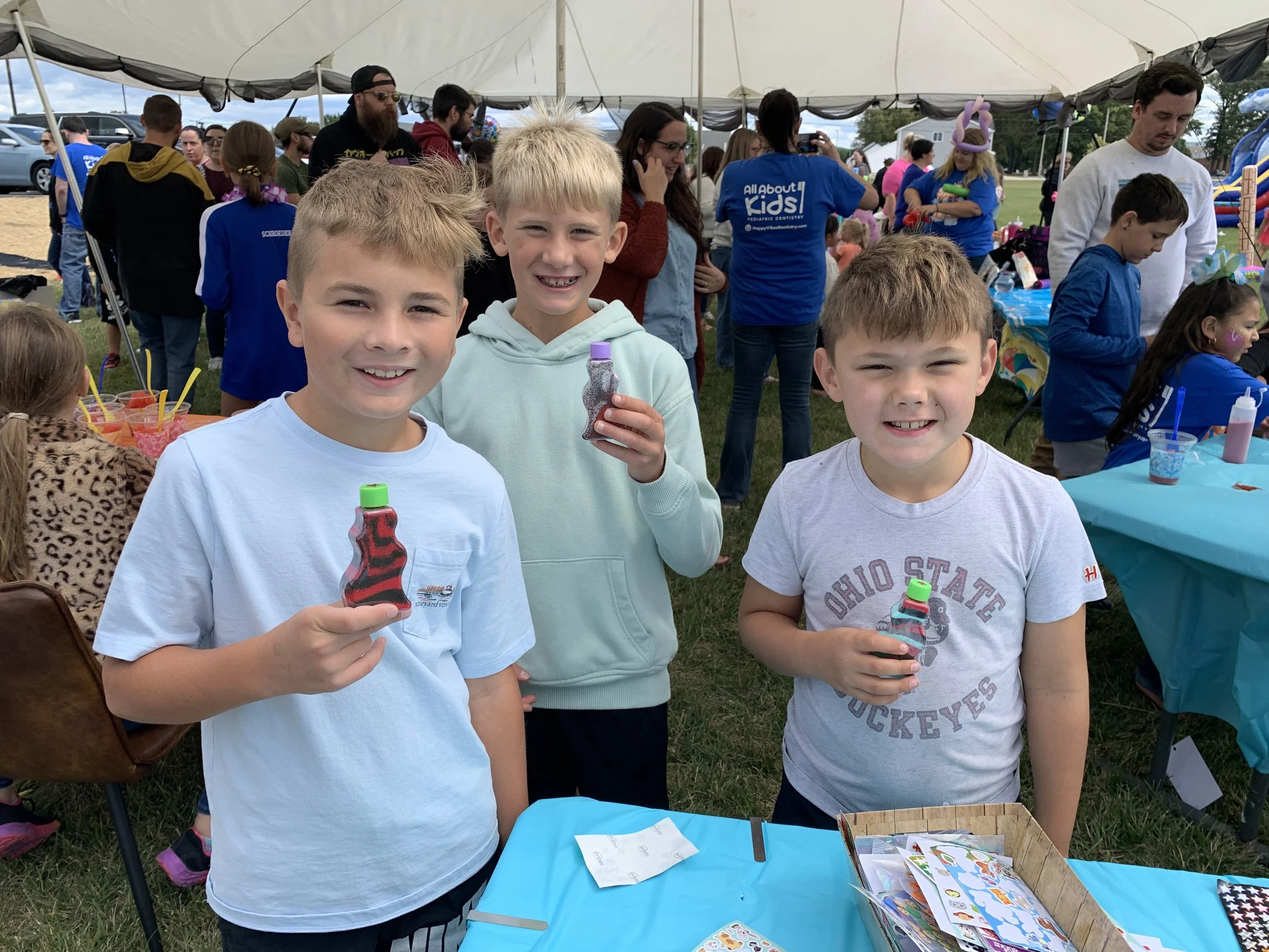 Children smiling and holding prizes at the Shine Ortho Studio open house during a community celebration.