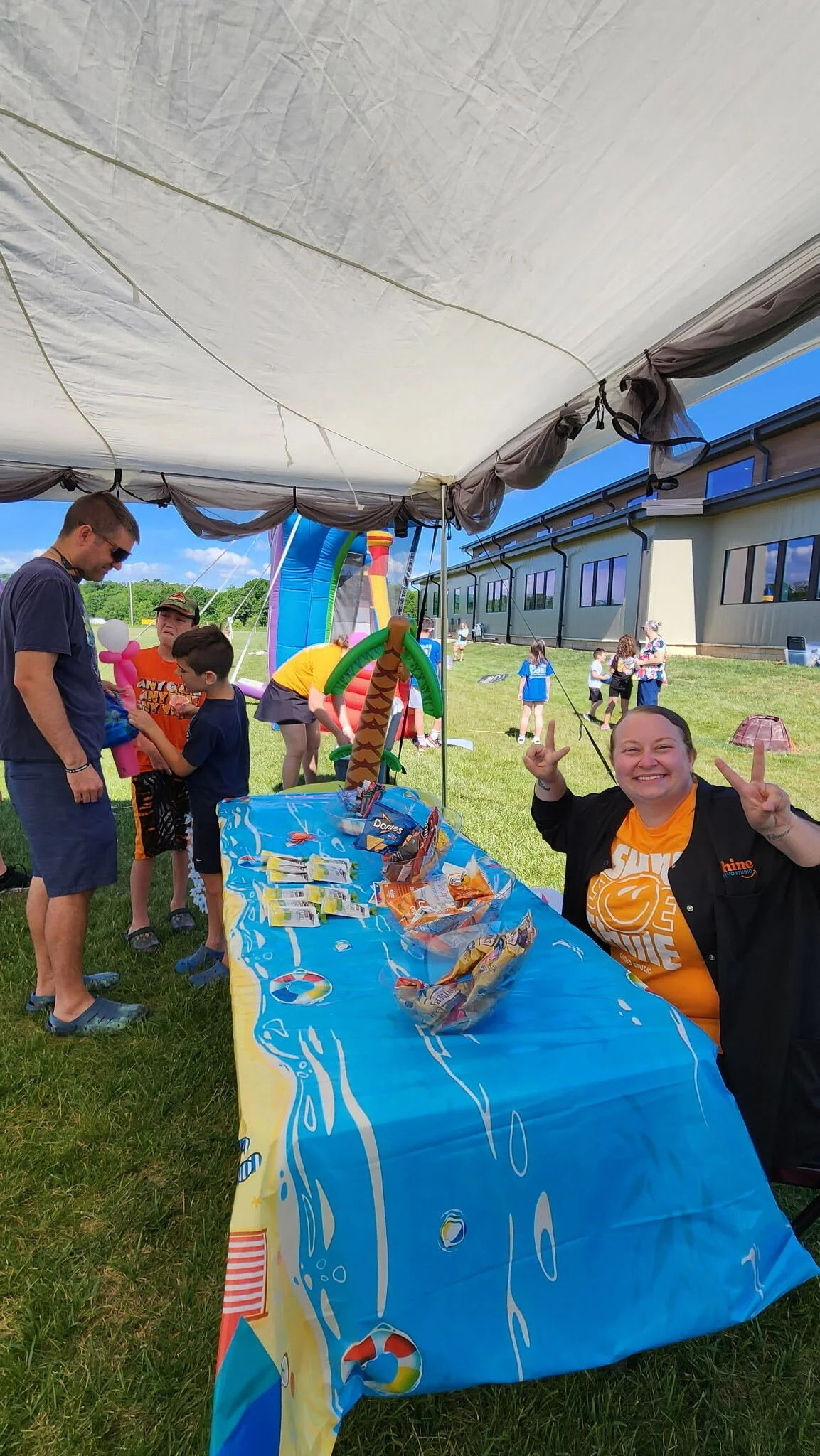 Shine Ortho Studio team member welcoming families at the prize table during the free Family Fun Day community event.